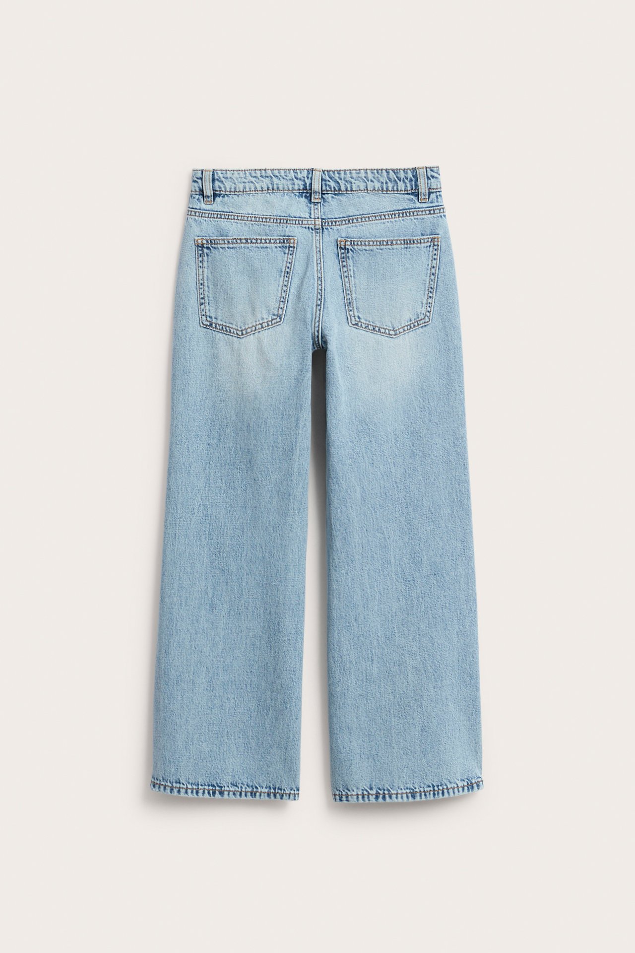 Widok z tyłu: jasnoniebieskie dżinsy dziecięce wide-leg z niskim stanem, bawełniane, z dwoma kieszeniami z tyłu.