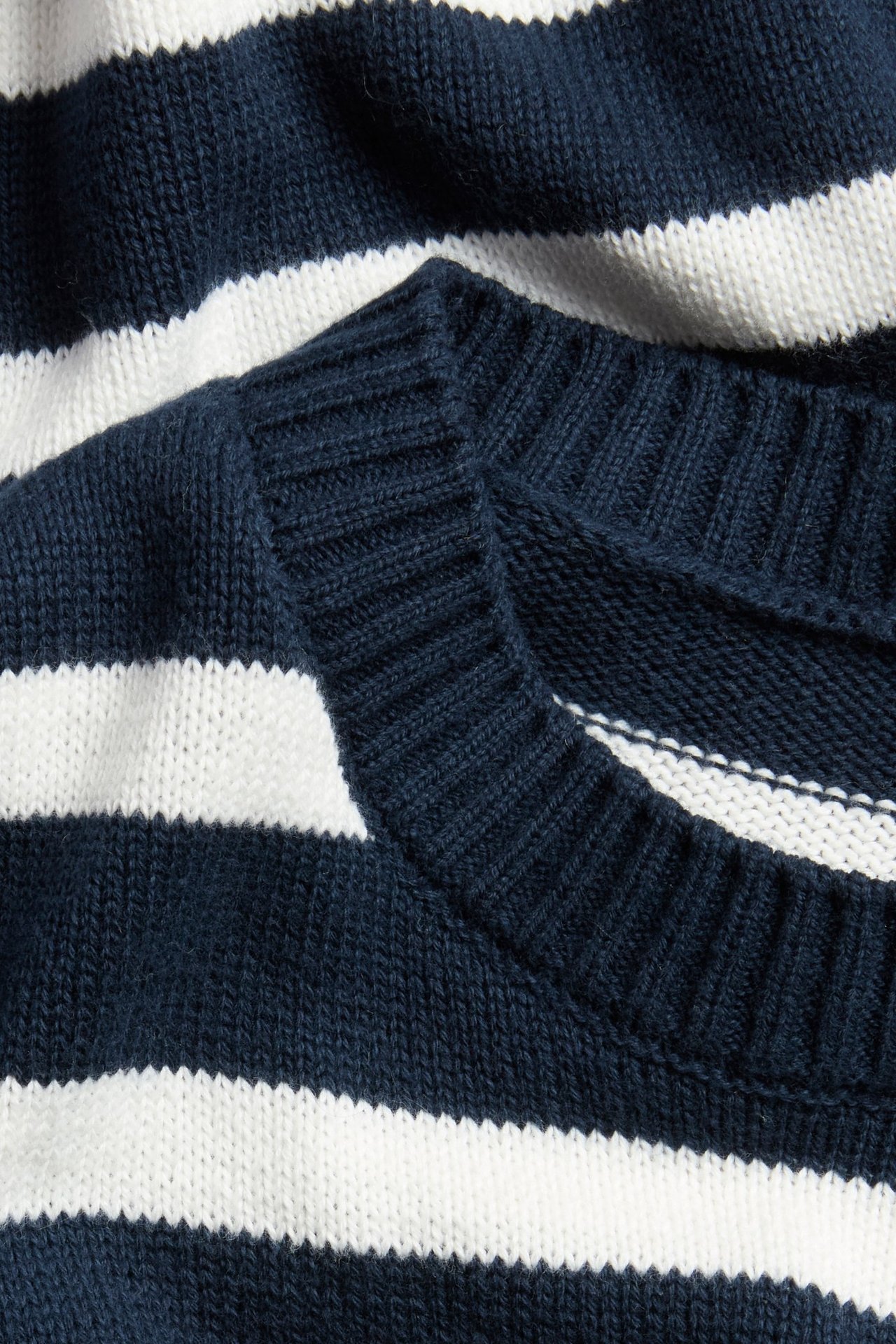 Lähikuva tummansinisestä ja valkoisesta raidallisesta neuleesta ribatulla pyöreällä pääntiellä.