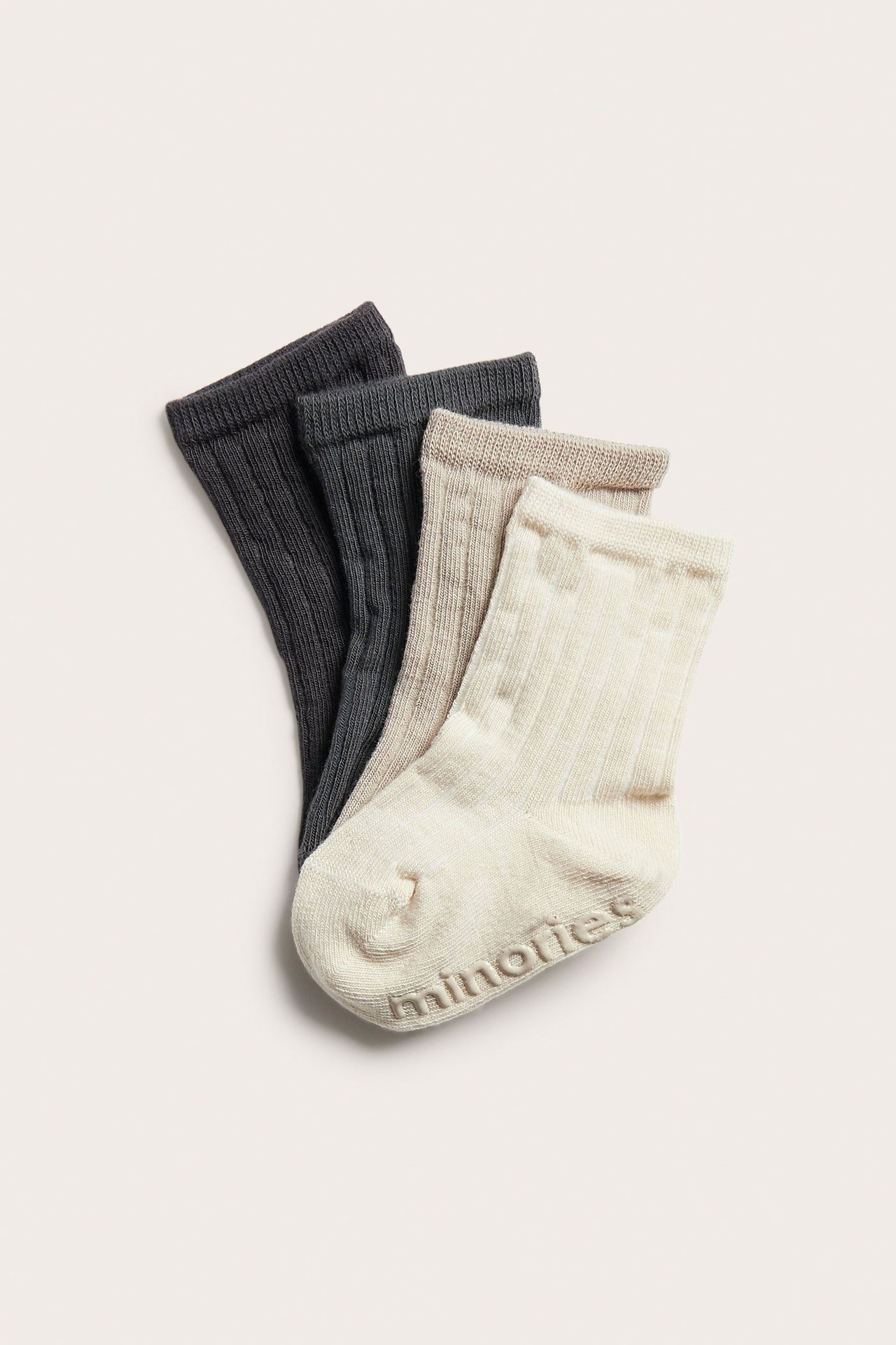 Lähikuva neljästä ribatusta vauvansukasta väreissä tummanharmaa, vaalea beige ja luonnonvalkoinen, 'minories'-logolla.