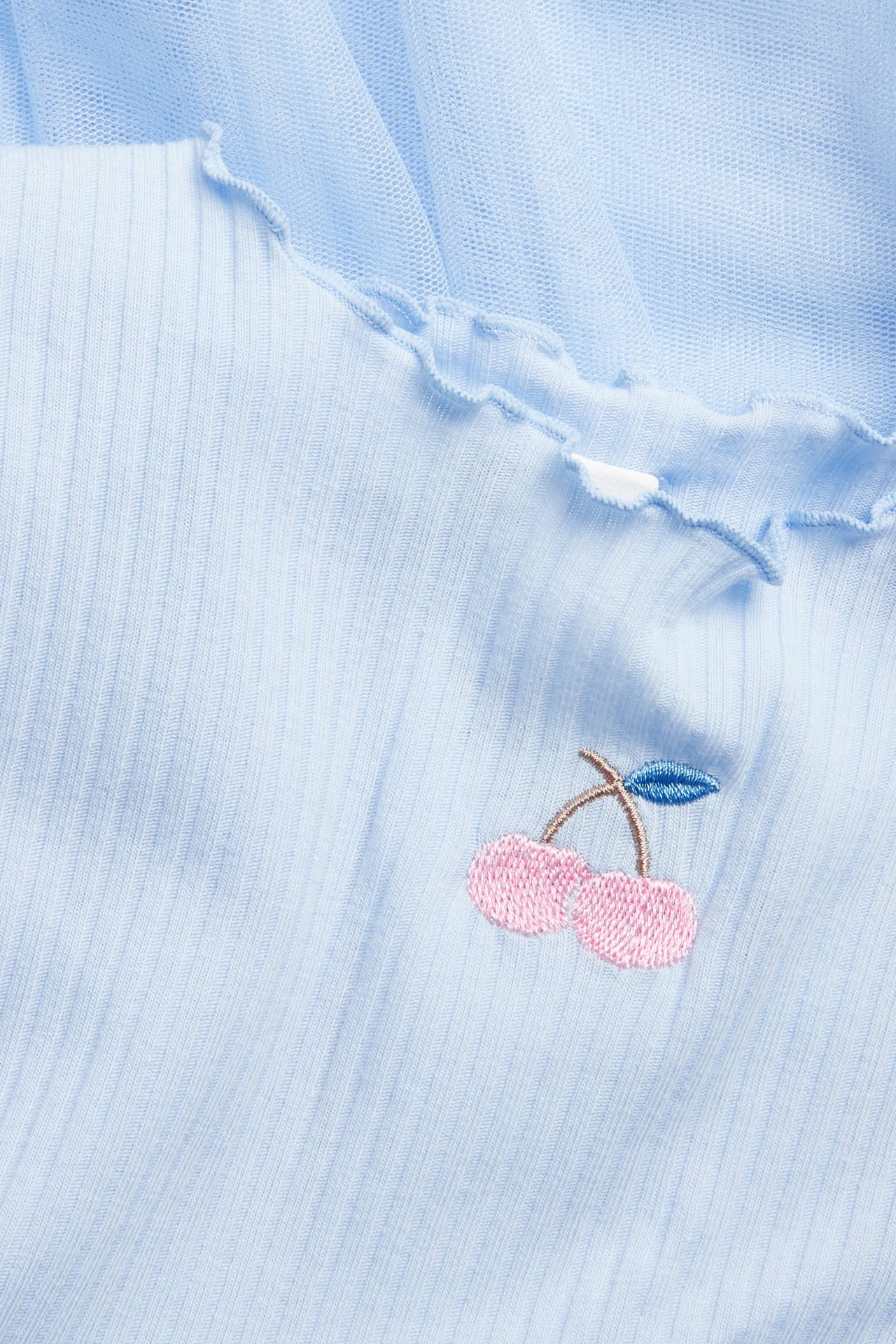 Zbliżenie na jasnoniebieską sukienkę dziecięcą z prążkowaną górą, babylock i haftem z wiśniami.