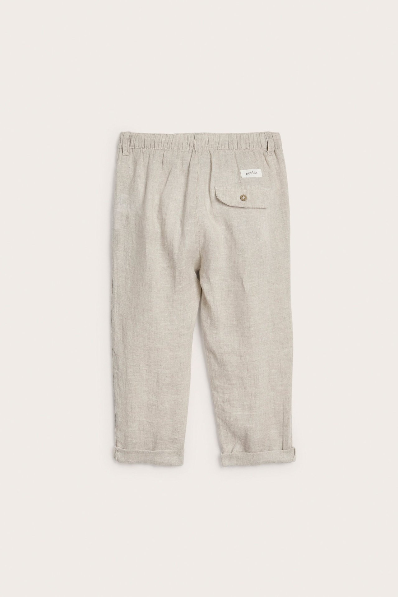 Bakifrån, ljusbeige linnebyxa för barn med resårmidja, knäppt bakficka och upprullade benslut.