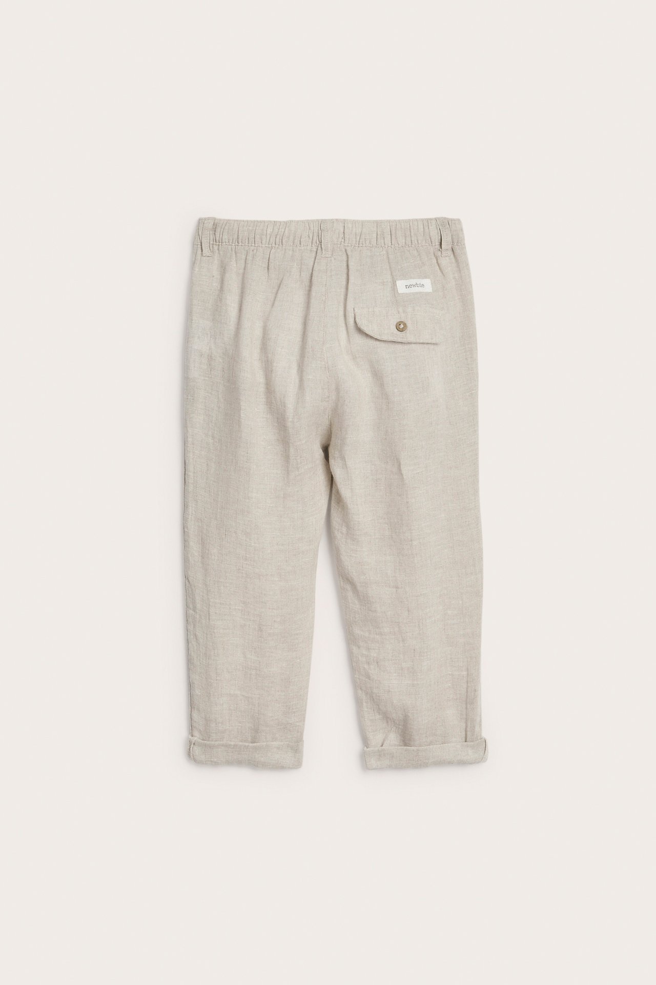 Bakfra, lys beige linstoffbukse for barn med elastisk midje, knappet baklomme og oppbrettede benkanter.