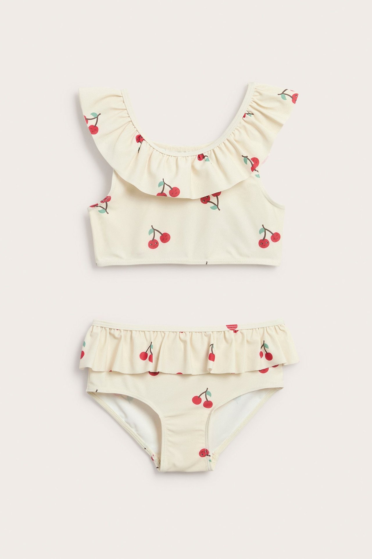 Edestäpäin: lasten vaalea beige bikini, jossa kirsikkakuvio ja röyhelöt ylä- ja alaosassa.
