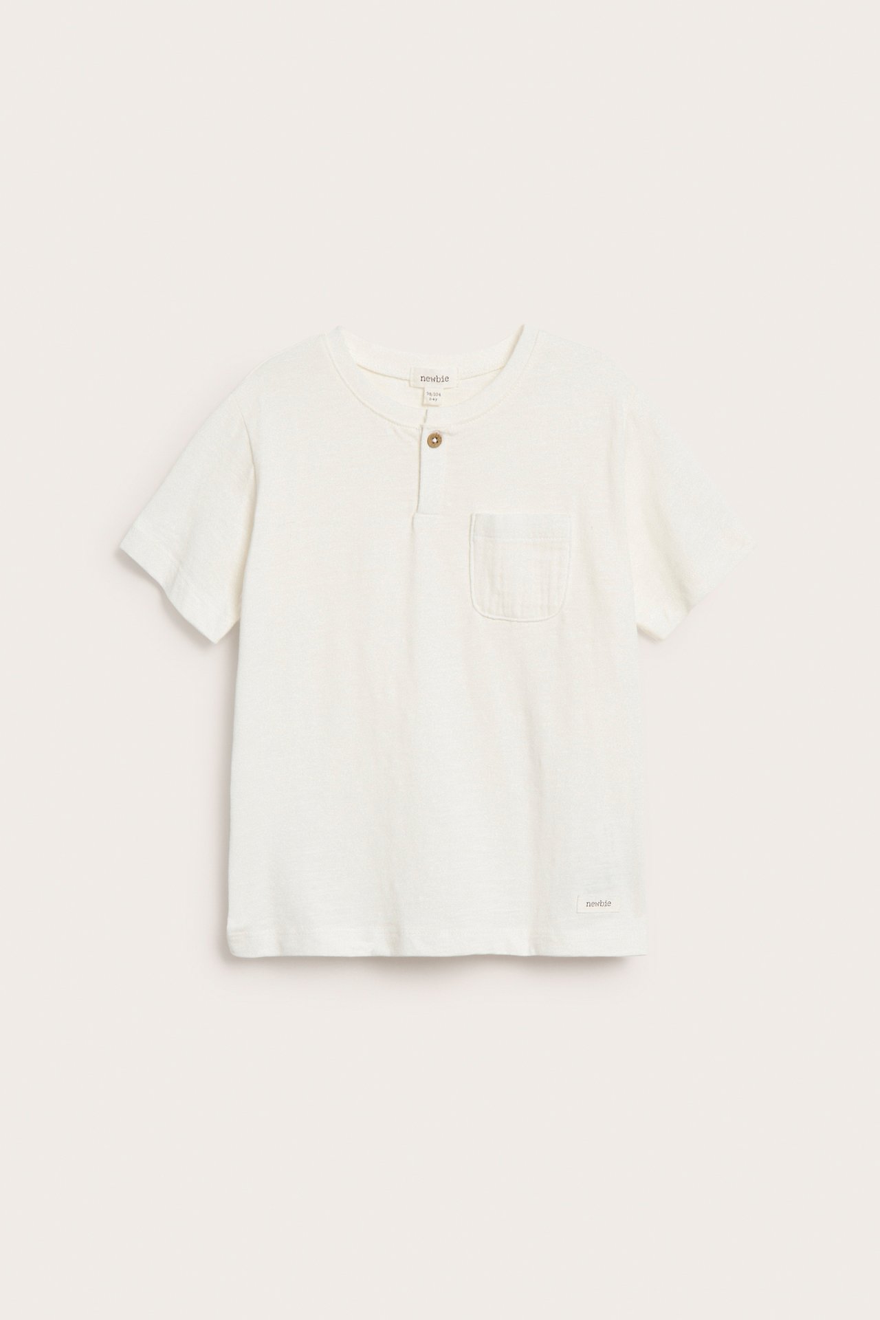Frontbilde av en offwhite slub-strikket T-skjorte for barn med knappestolpe og brystlomme.