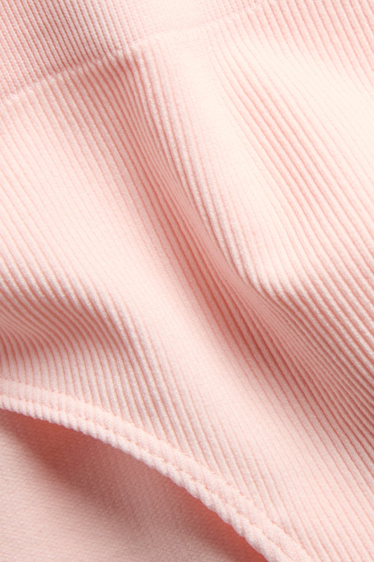 Zbliżenie na jasnoróżowe bezszwowe prążkowane figi typu hipster, pokazujące teksturowany materiał.