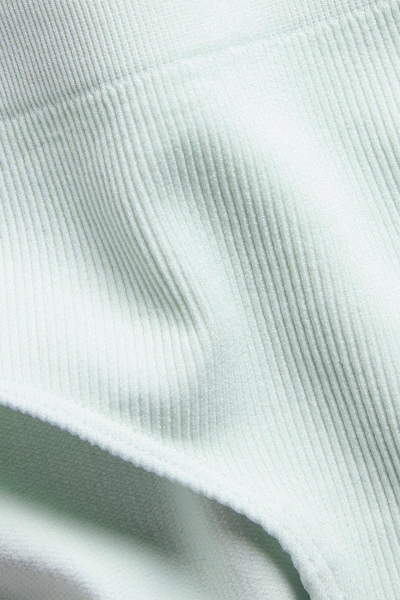 Zbliżenie na jasnozielony, bezszwowy, prążkowany materiał fig typu hipster.