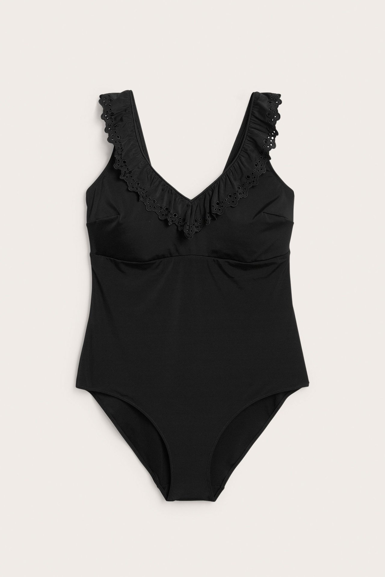 Edestä: Musta yksiosainen uimapuku, jossa V-pääntie ja pitsireunaiset röyhelöt olkaimissa.