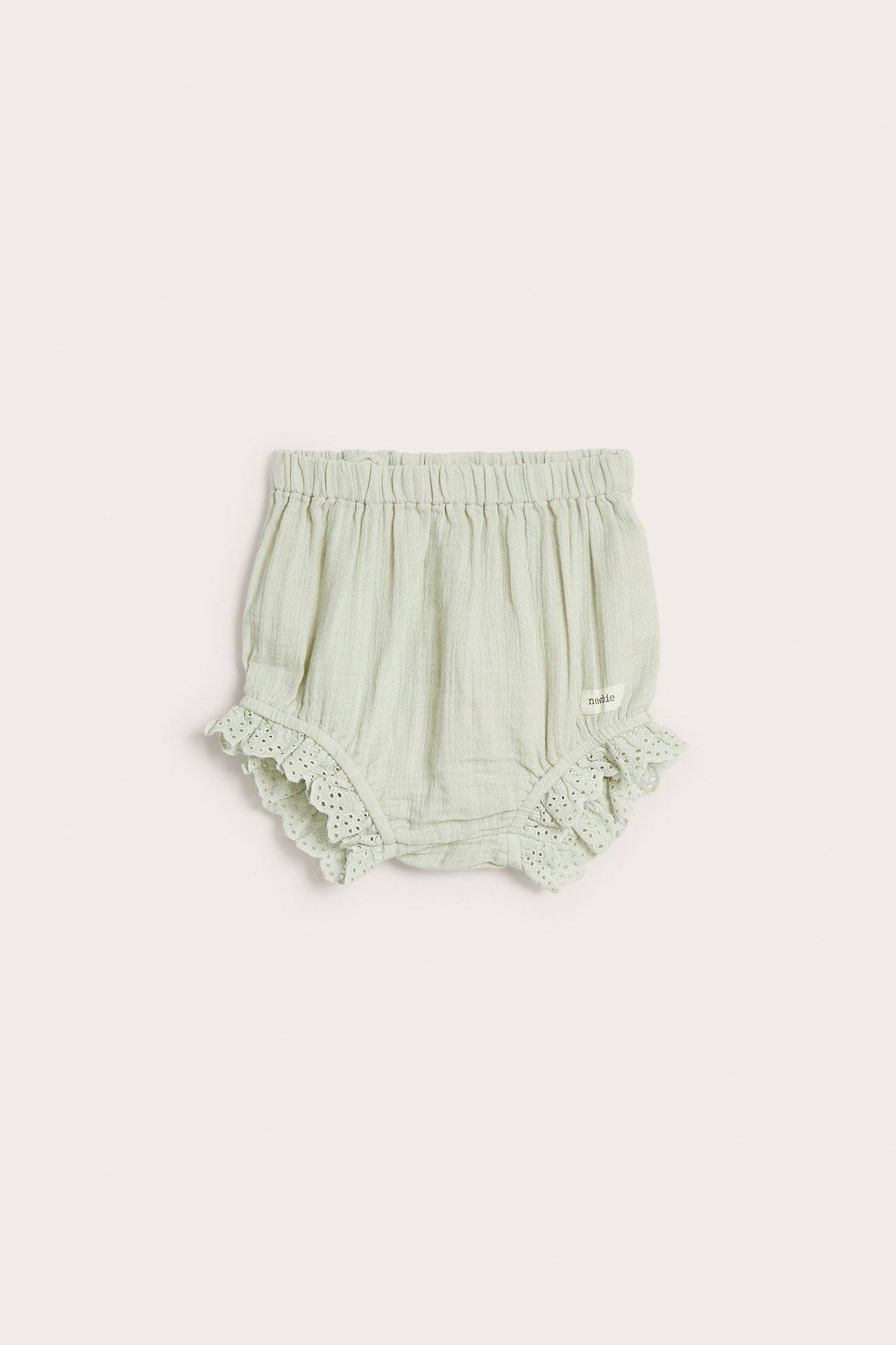Forfra lysegrønne vevde bomulls-babyshorts med elastisk midje og blondevolanger.