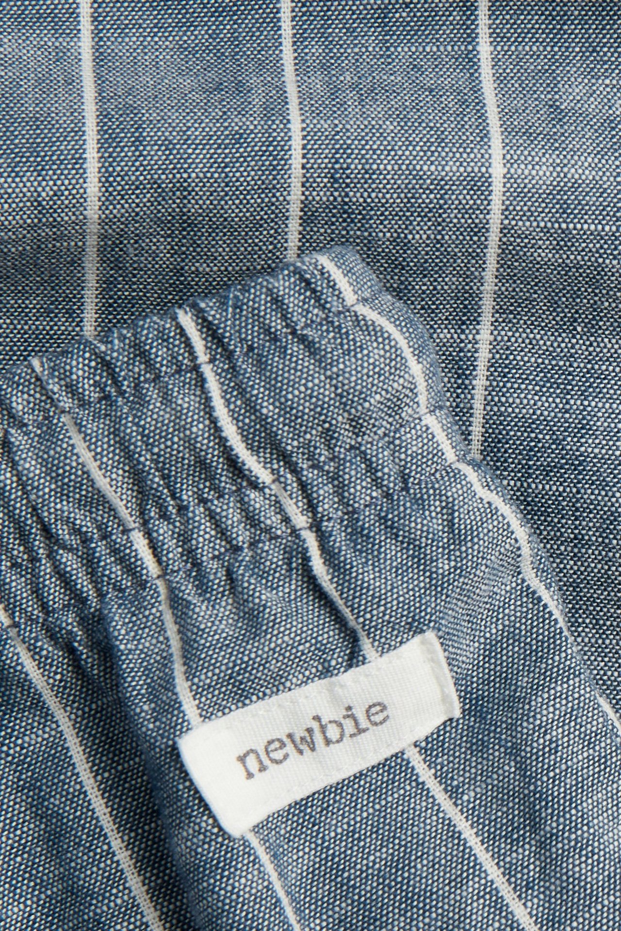 Lähikuva sinivalkoraidallisista puuvillahousuista, joissa joustava vyötärö ja 'Newbie'-merkki.