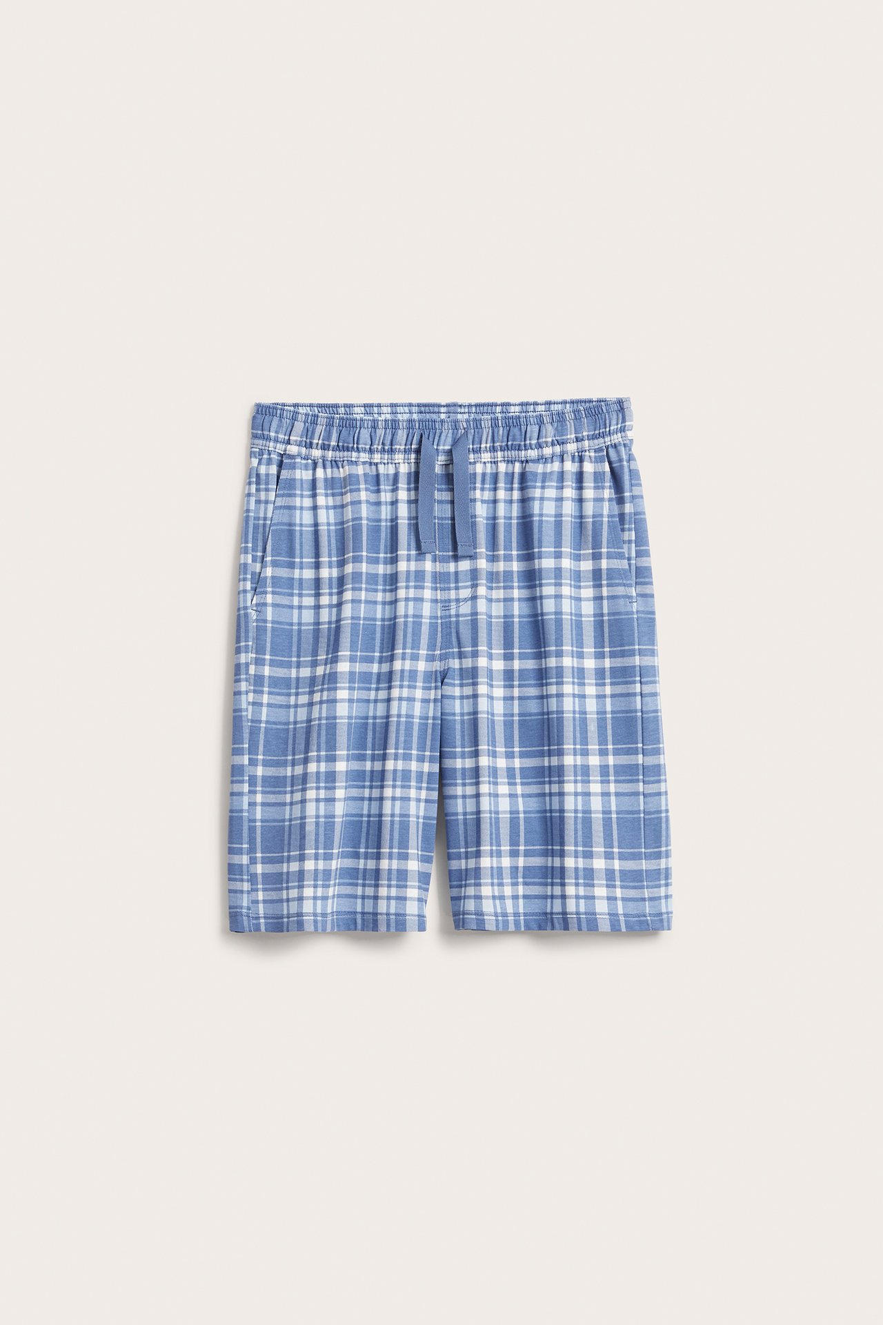 Edestäpäin kuvatut sinivalkoruudulliset puuvillatrikoopyjamashortsit, joissa joustovyötärö ja kiristysnyöri.