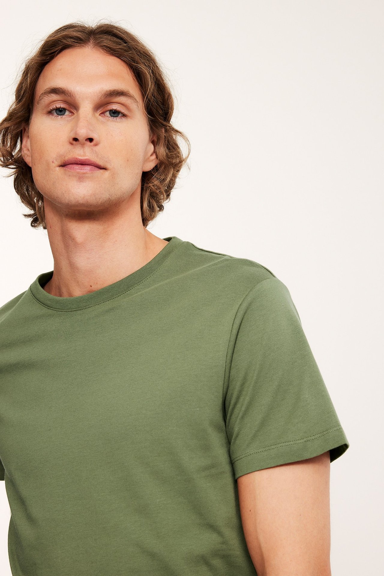 Nærbilde av en mann som har på seg en ensfarget kakigrønn rundhalset bomulls-T-skjorte.