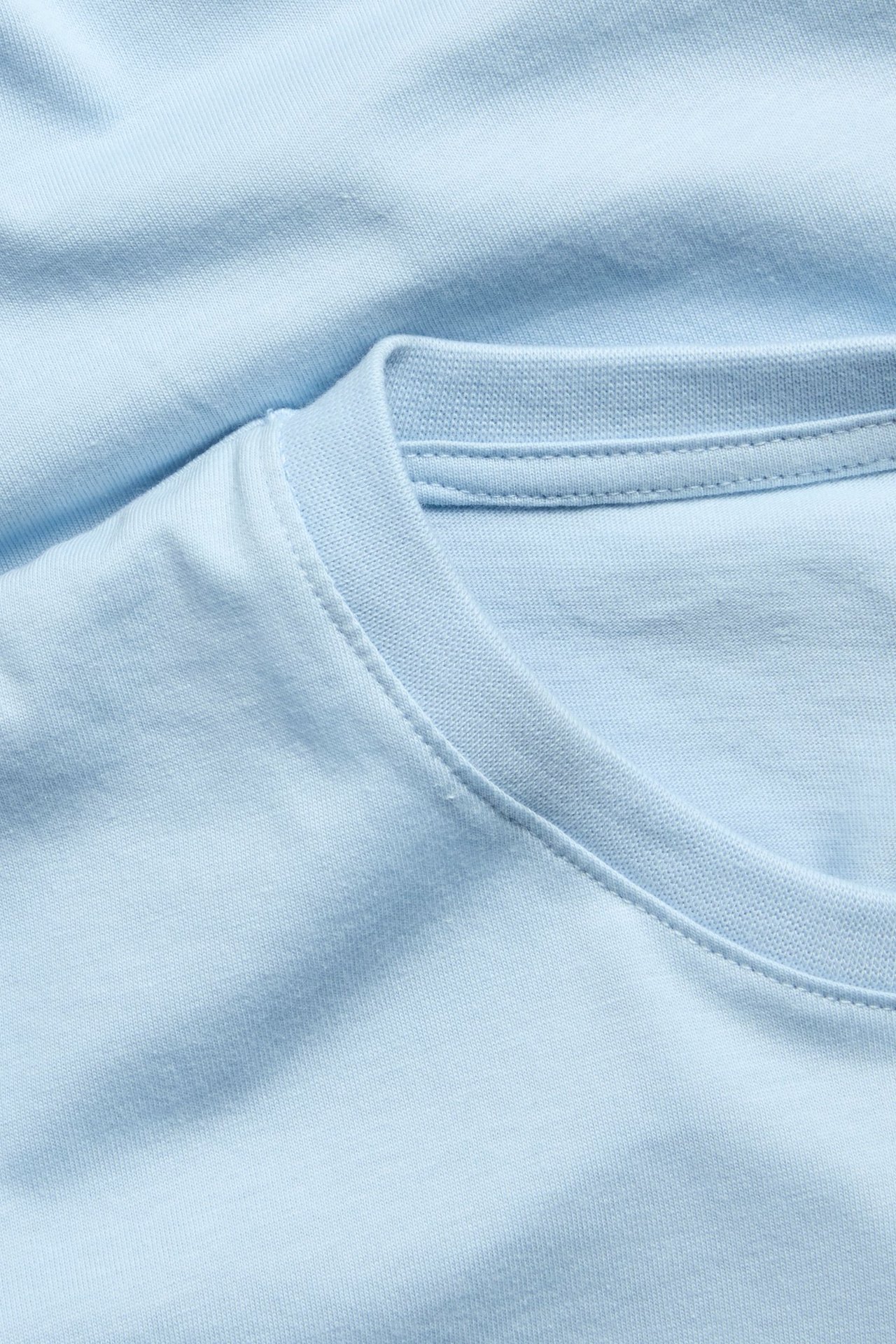 Zbliżenie jasnoniebieskiego męskiego t-shirtu z bawełny organicznej z okrągłym dekoltem.