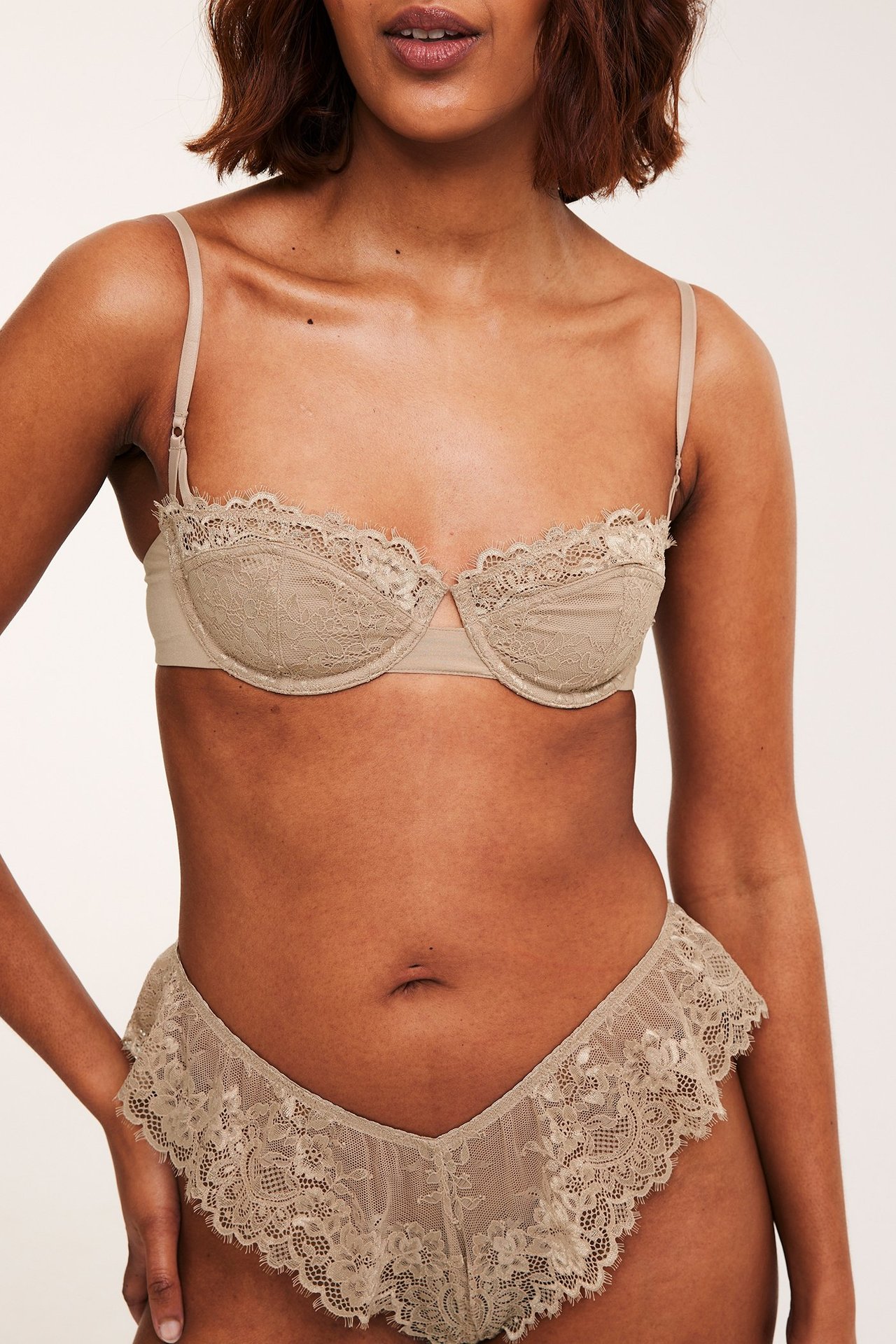 Framifrån: kvinna i brun spetsbalconette-bh och matchande spetstrosor.