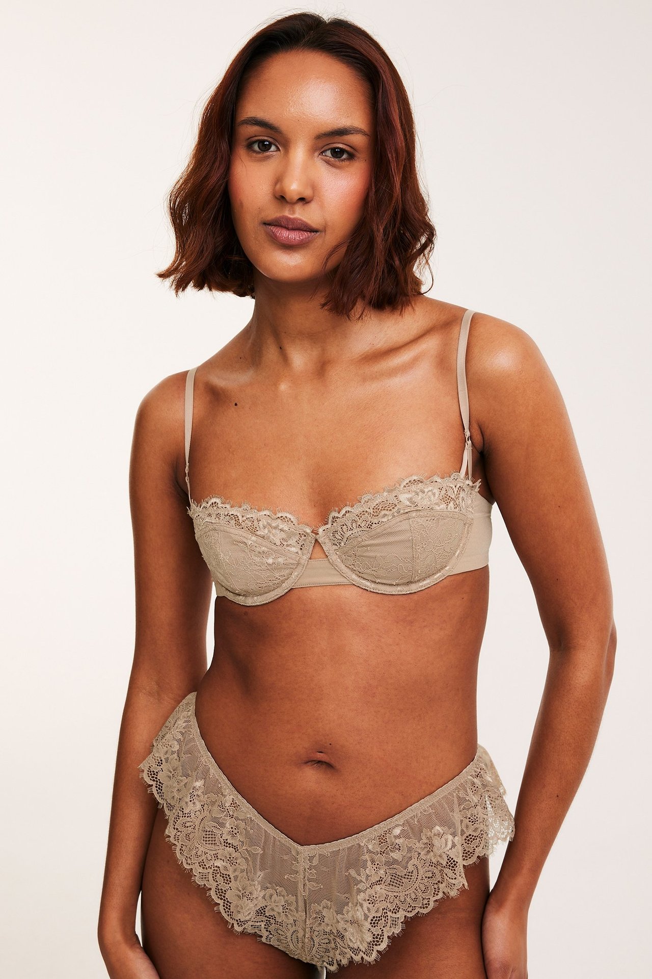 Forfra av kvinne i lysbrun blonde-balconette-bh og matchende blondetruse.