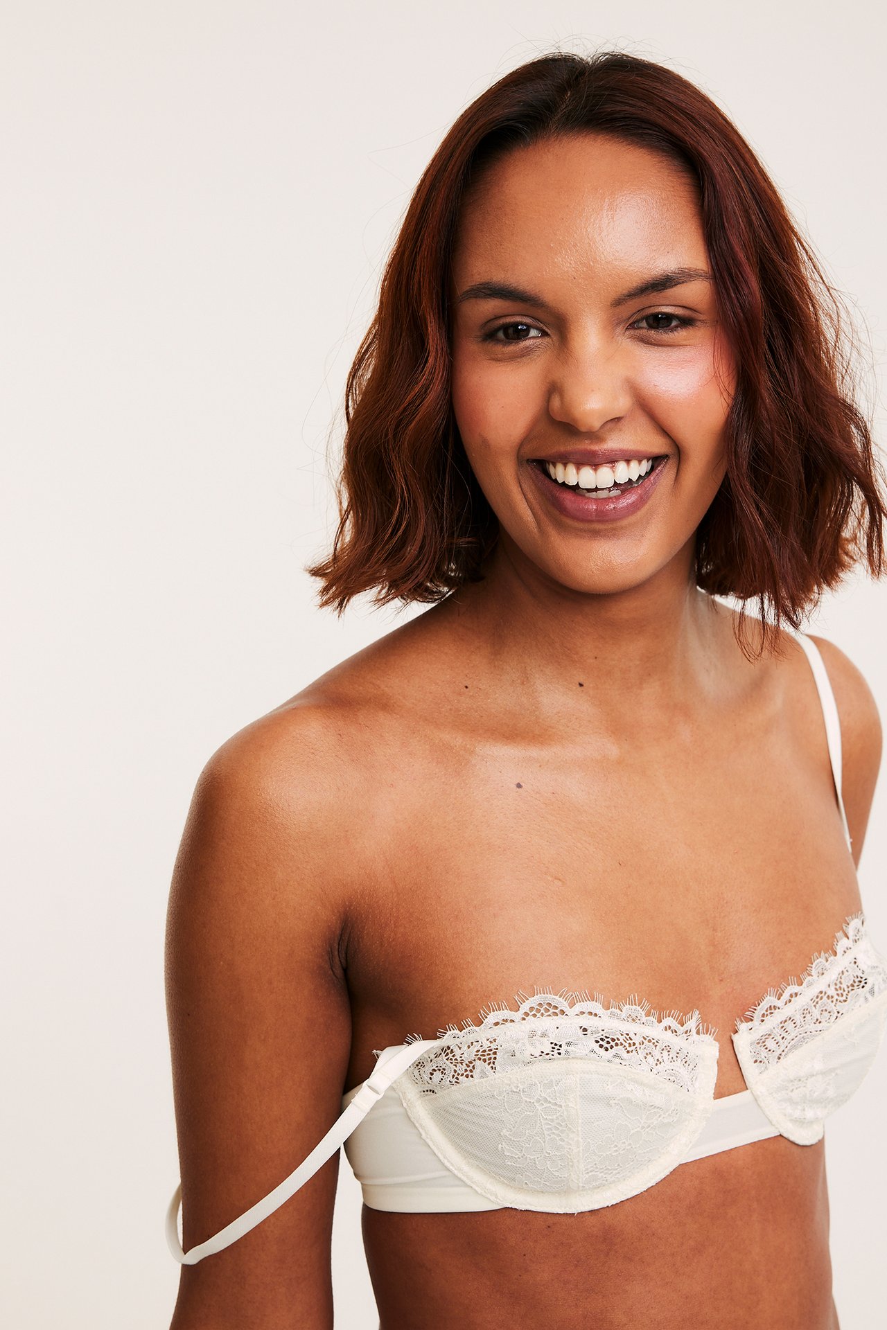 Nærbilde av en kvinne i en offwhite blonde-balconette-BH, med en stropp nede.