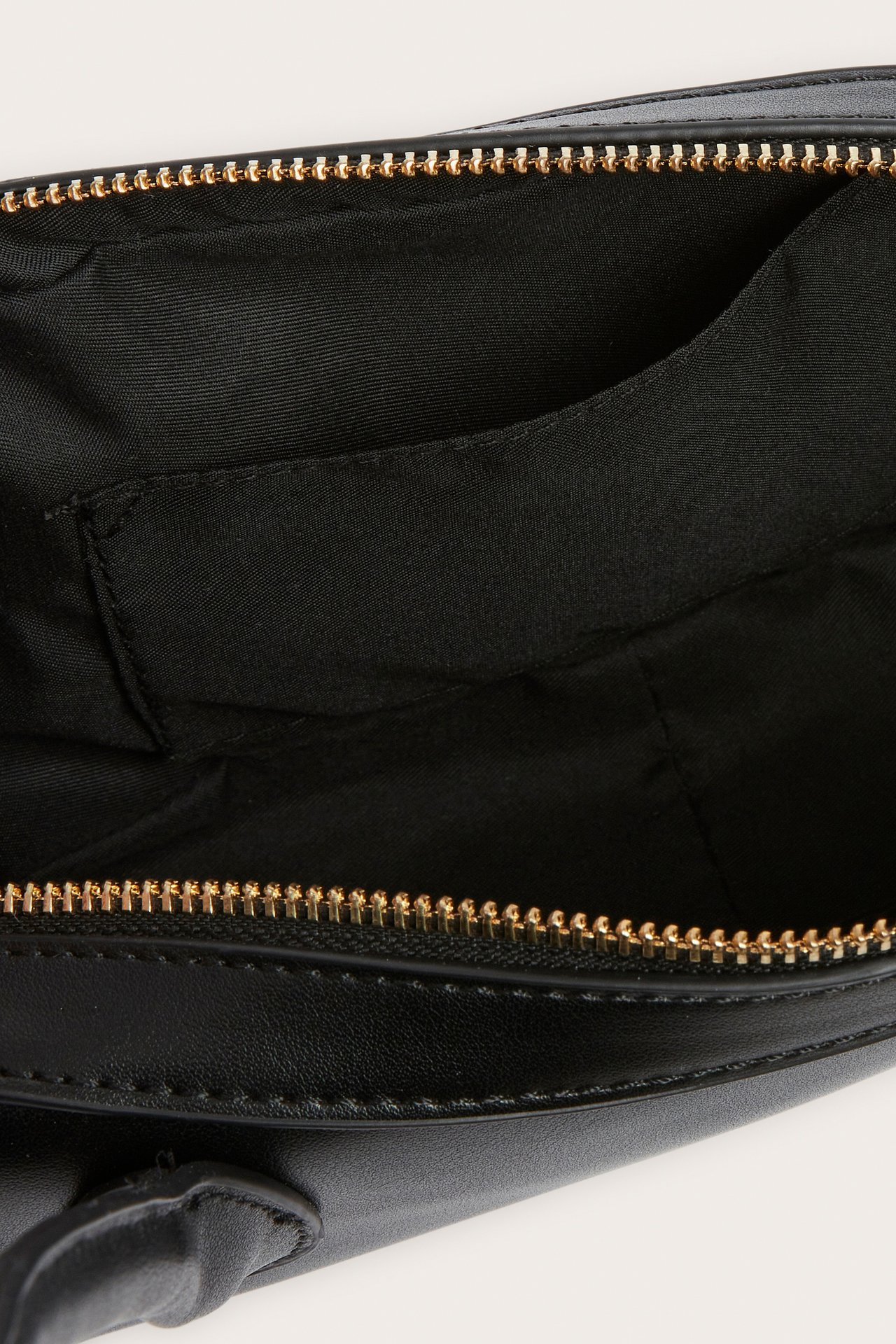 Lähikuva avoimesta mustasta bowlinglaukusta, jossa kultainen vetoketju, musta vuori ja sisätasku.