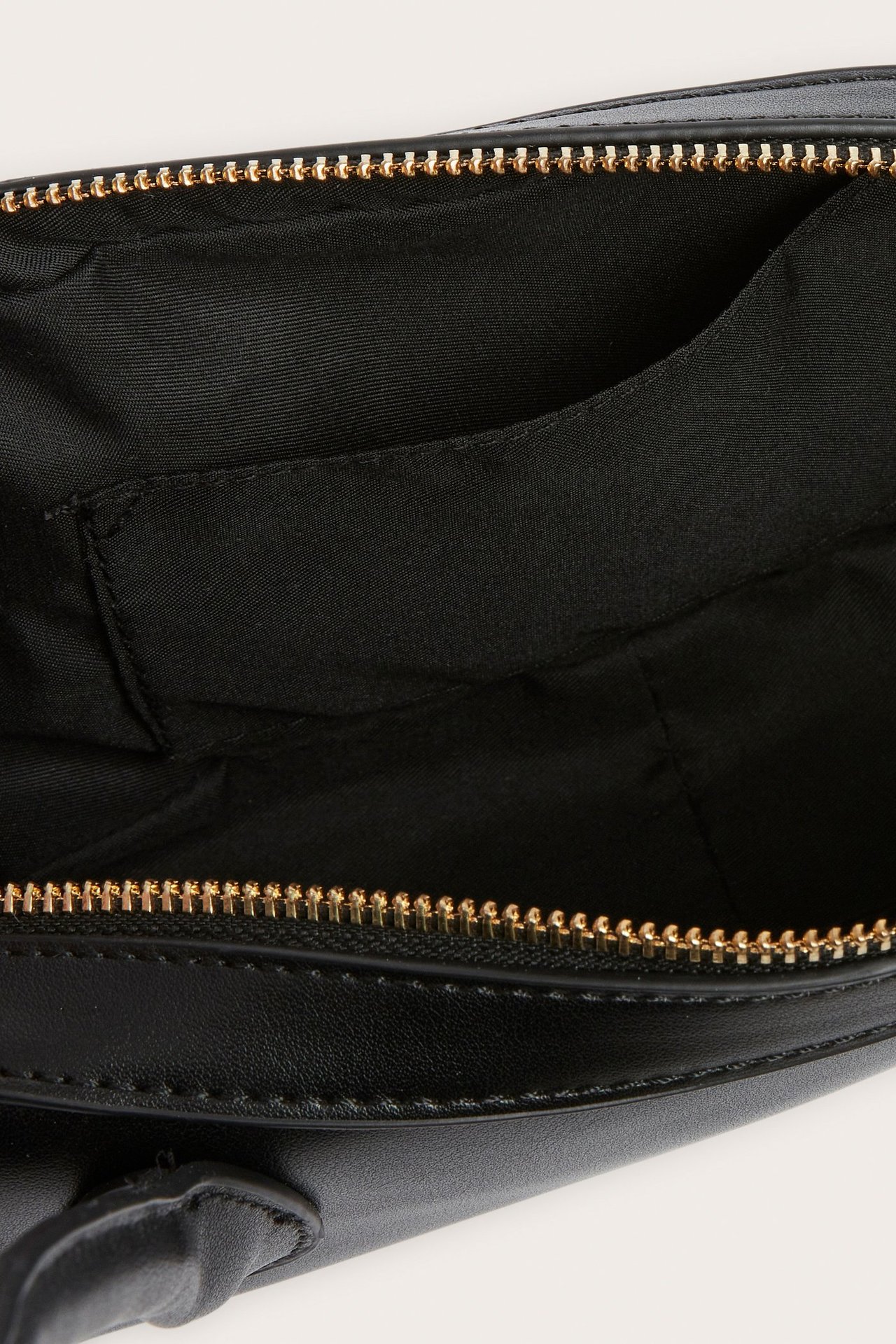 Nærbilde av den åpne svarte bowlingbagen, viser gullfarget glidelås, svart fôr og innerlomme.