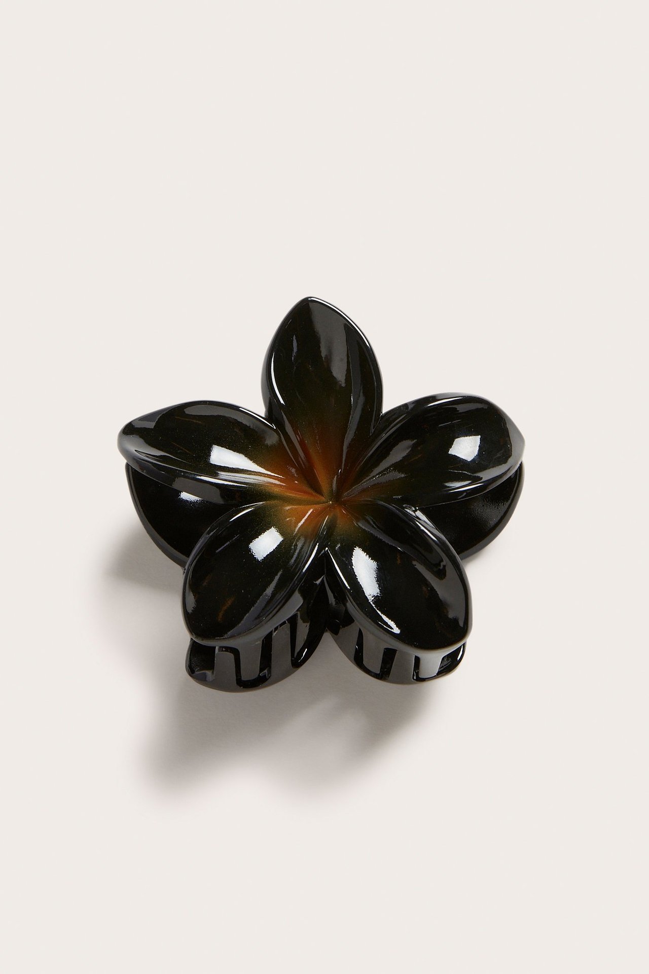 Uppifrån sett, svart blomformad hårklämma av återvunnen plast.