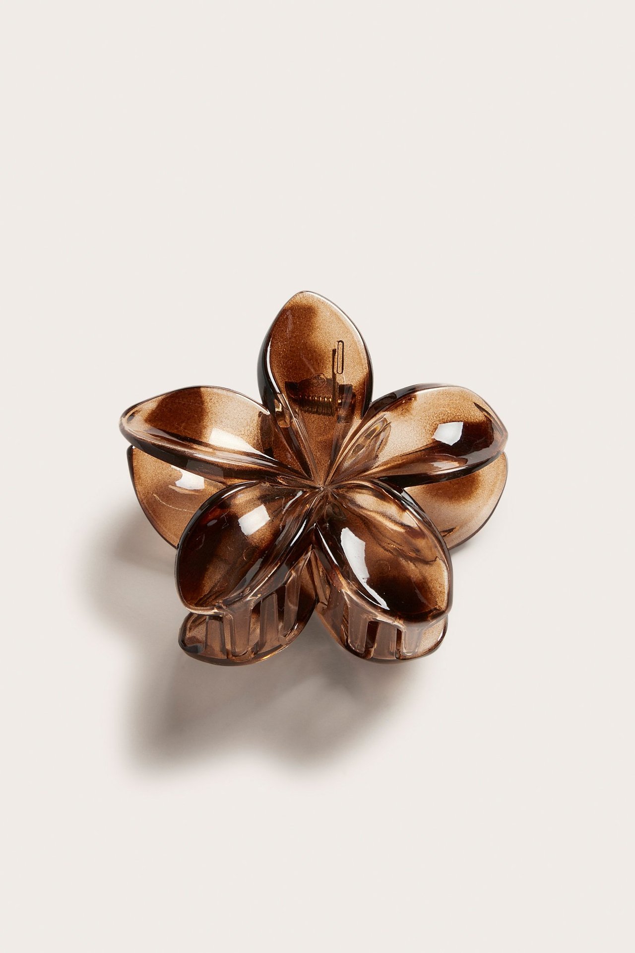 Närbild framifrån på en brun blomformad hårklämma av återvunnen plast.