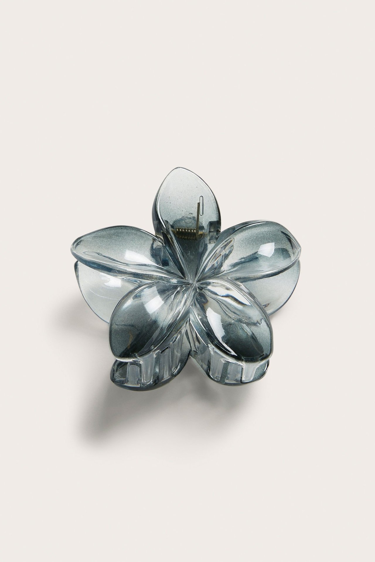 Närbild, uppifrån, av en mörkblå, genomskinlig blomformad hårklämma av återvunnen plast.