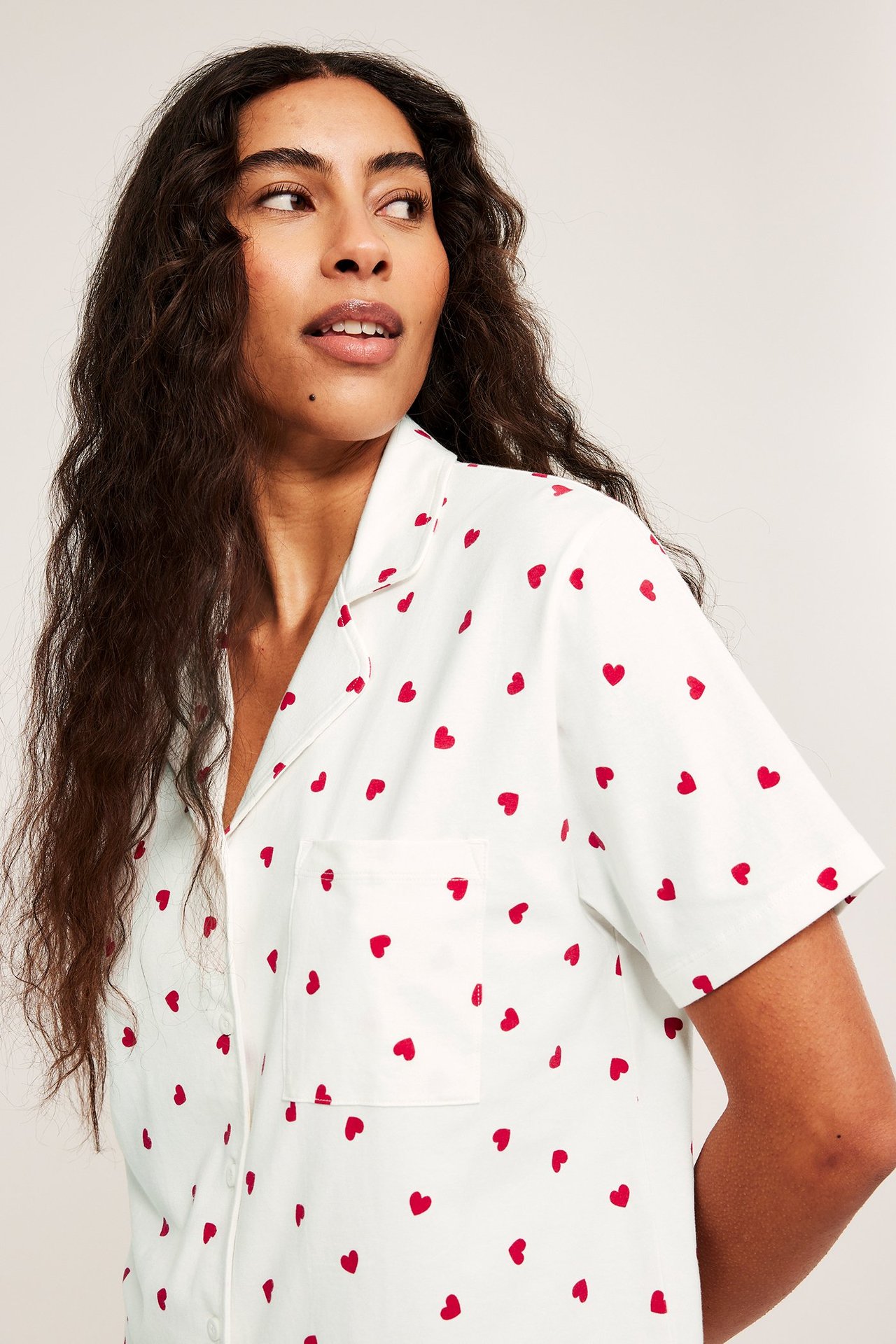 Zbliżenie kobiety w kremowej piżamie bawełnianej z krótkim rękawem i czerwonym wzorem serc.