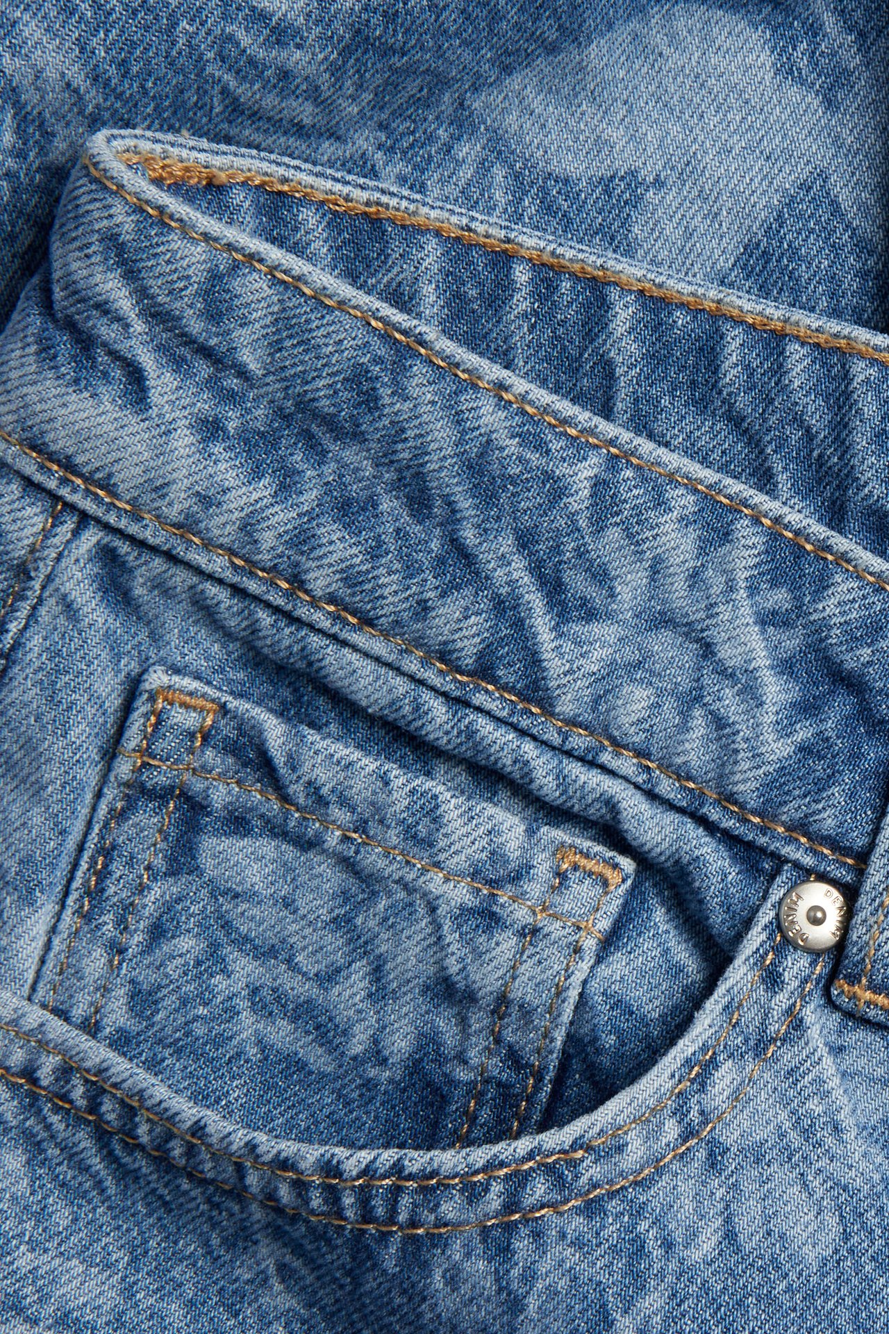 Lähikuva vaaleansinisistä, pestyn denim-kankaan korkeavyötäröisistä farkuista kolikkotaskulla.