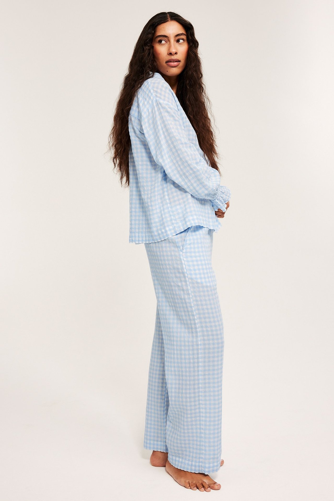 Sidebilde av en kvinne i lyseblå- og hvitrutete seersuckerpyjamas.