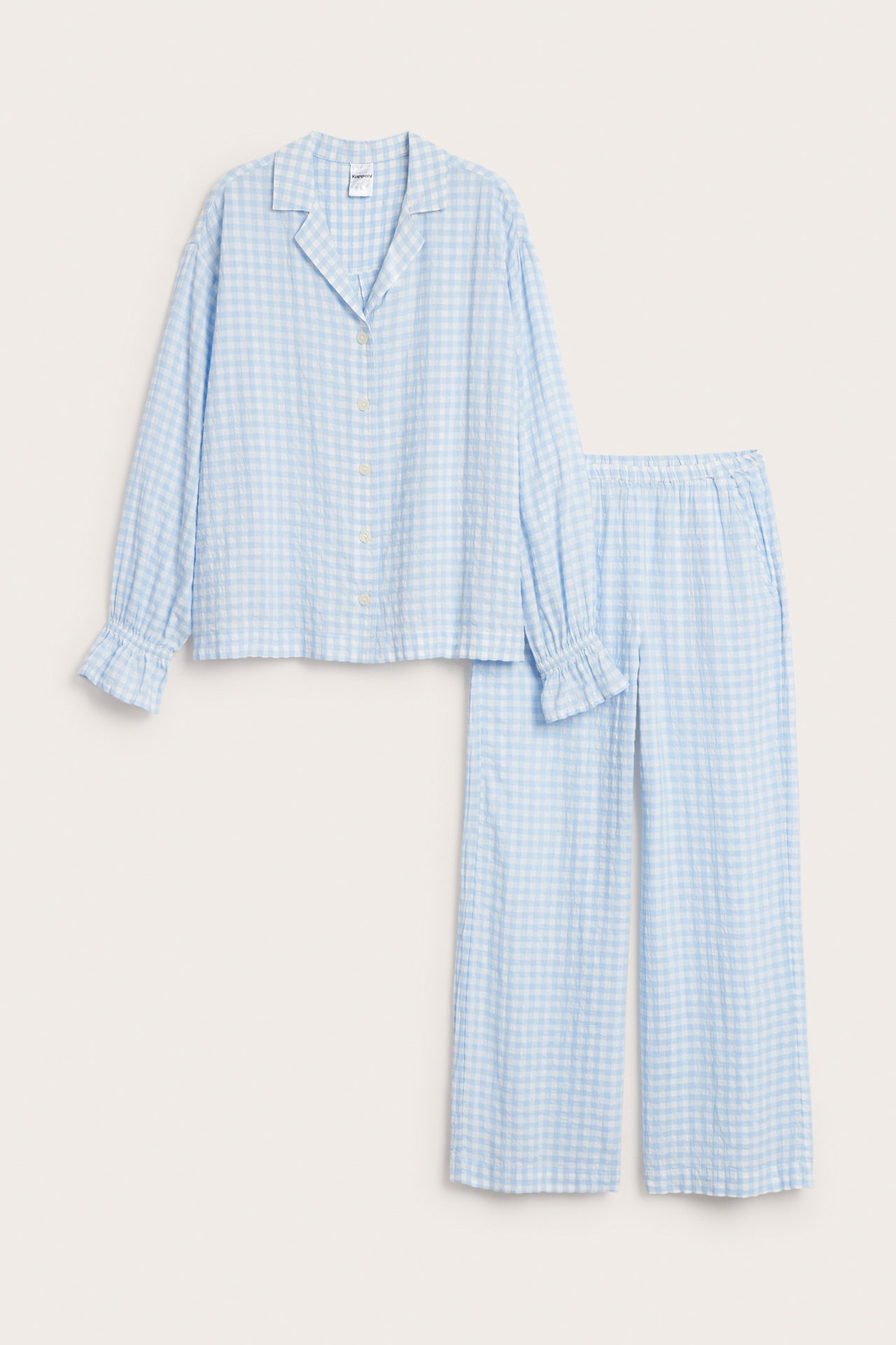 Forfra: Et lyseblått og hvitt rutete seersucker-pyjamassett, med kneppet skjorte og vide bukser.
