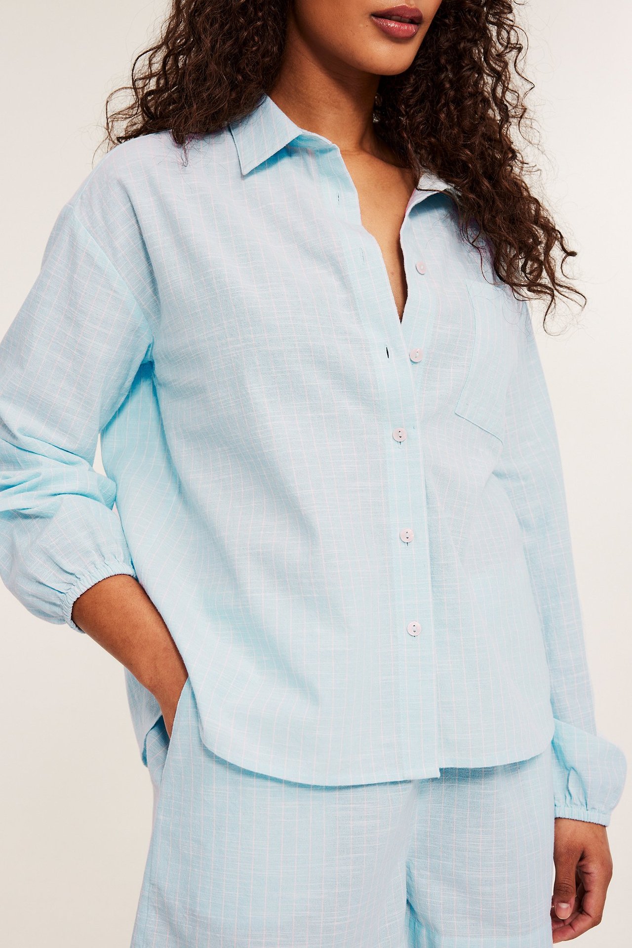 Edestäpäin, nainen yllään vaaleansininen kuviollinen puuvillapyjama: paita rintataskulla ja shortsit.