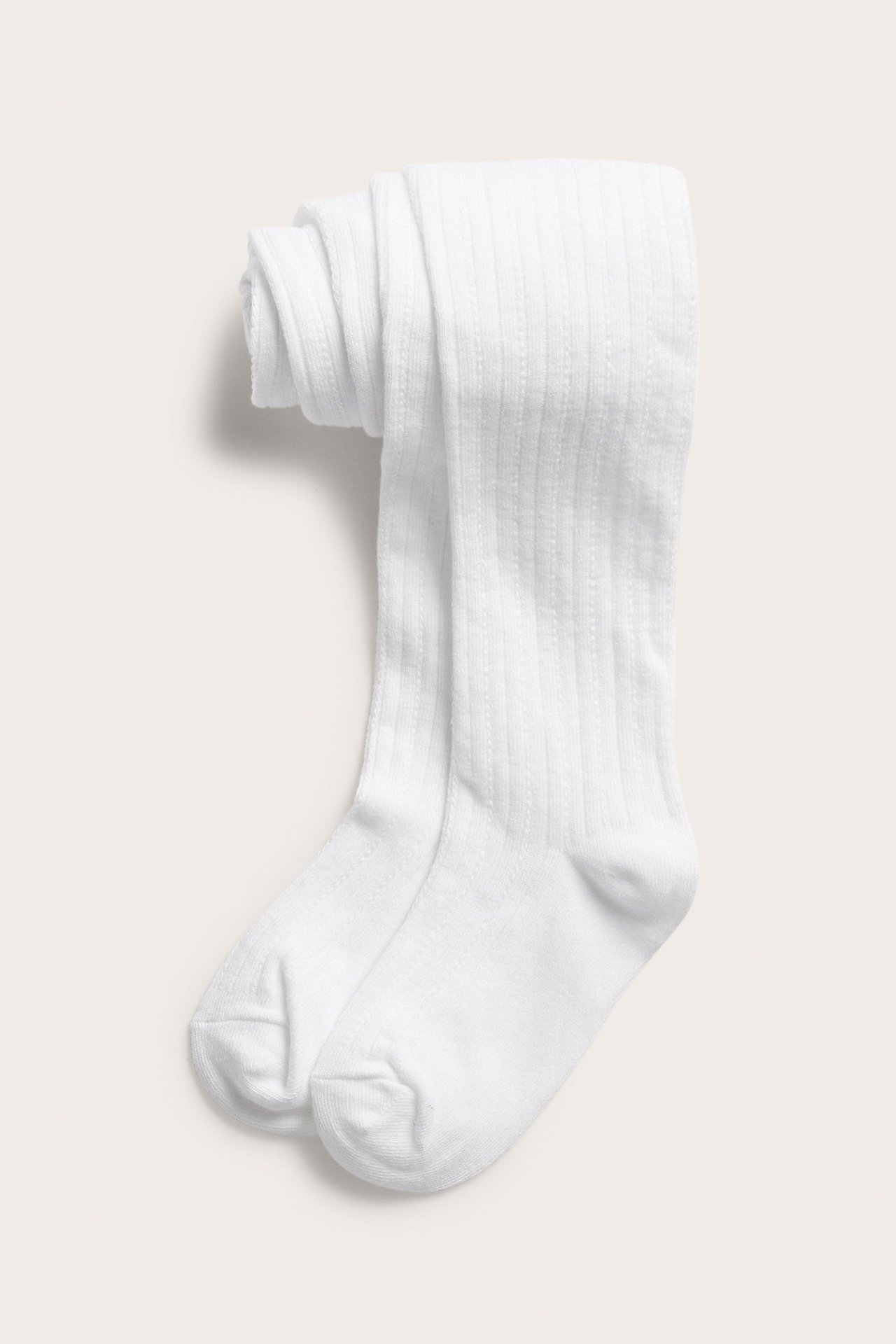 Frontvy av vikta vita mönsterstickade barnstrumpbyxor med subtil ribbad struktur.
