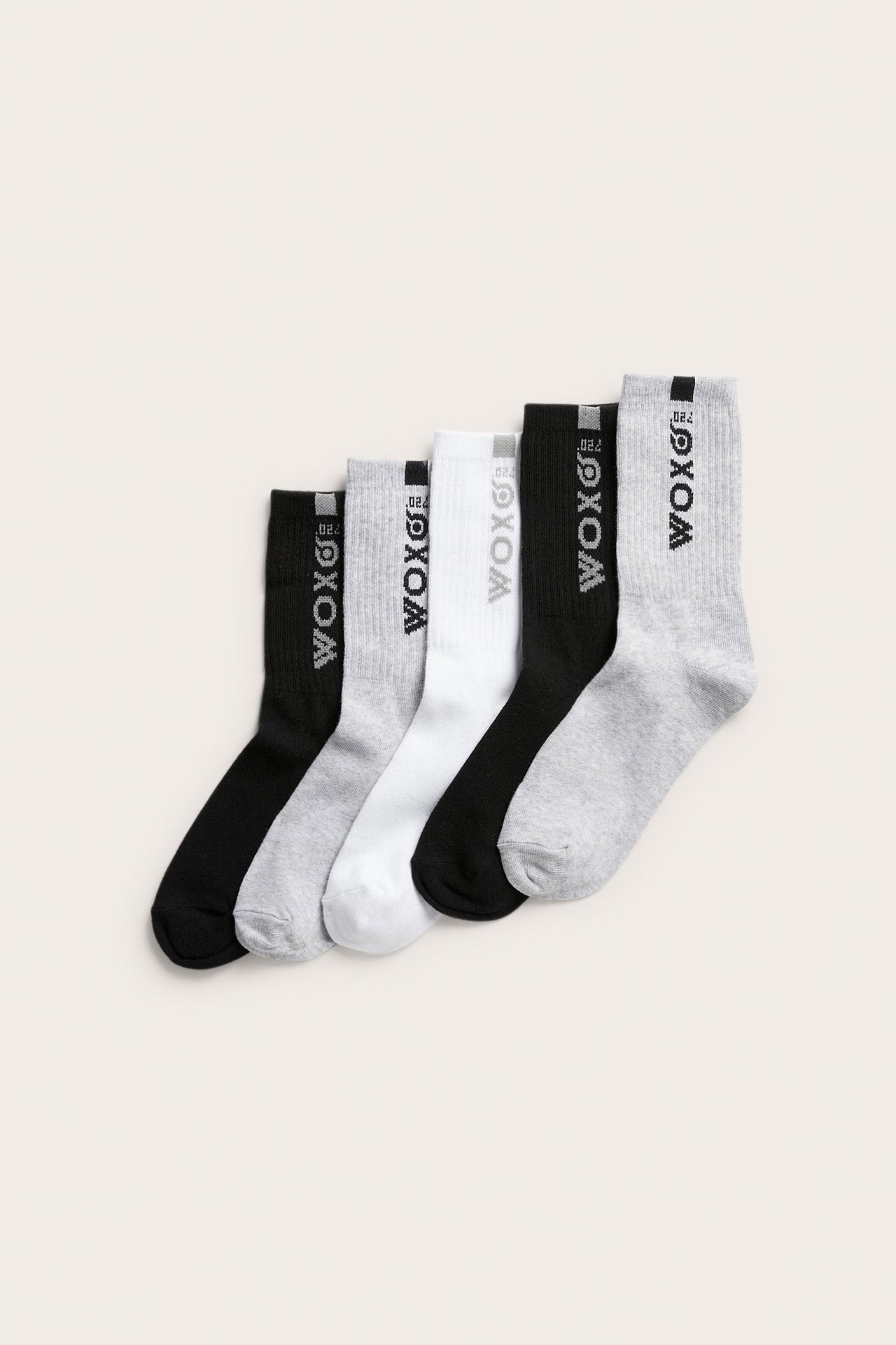 Ylhäältä: Viiden sukan pakkaus mustia, vaaleanharmaita ja valkoisia ribattuja sukkia painatuksella.