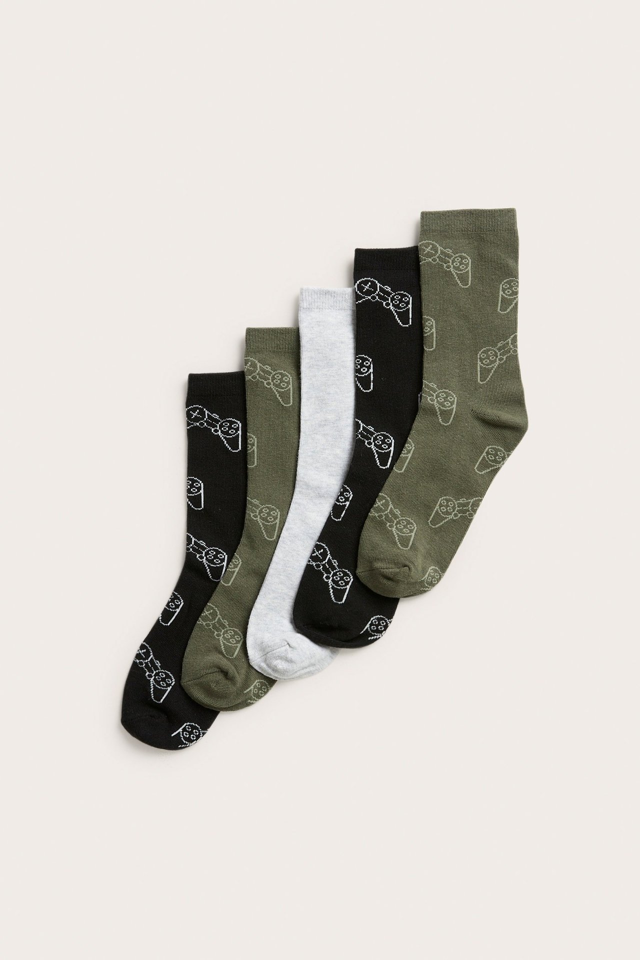 Fem mönstrade barnstrumpor i grönt, svart, grått med spelkontroller. Ovanifrån.