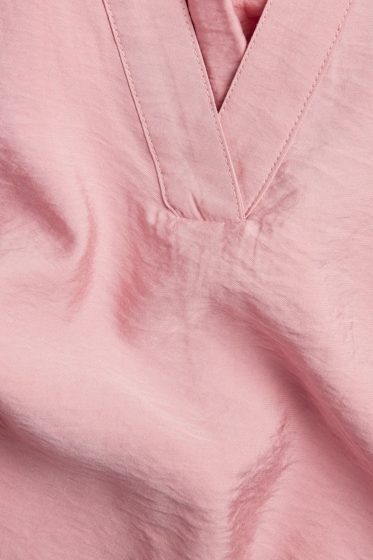 Nærbilde av en rosa popover-bluse med v-hals, laget av en viskoseblanding.