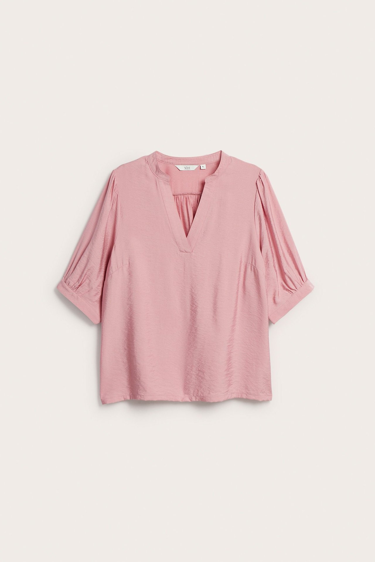 Frontalvisning av en rosa popover-bluse med V-hals, 3/4 puffermer og en diskret glans.