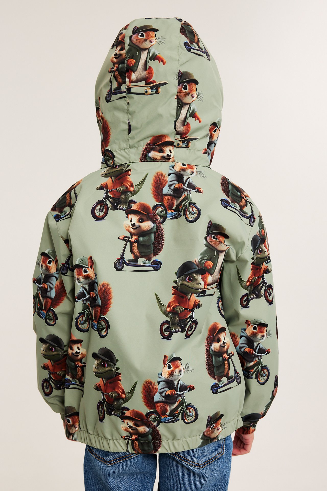 Ryggvy av ett barn i en ljusgrön mönstrad jacka med djurtryck och blå jeans.