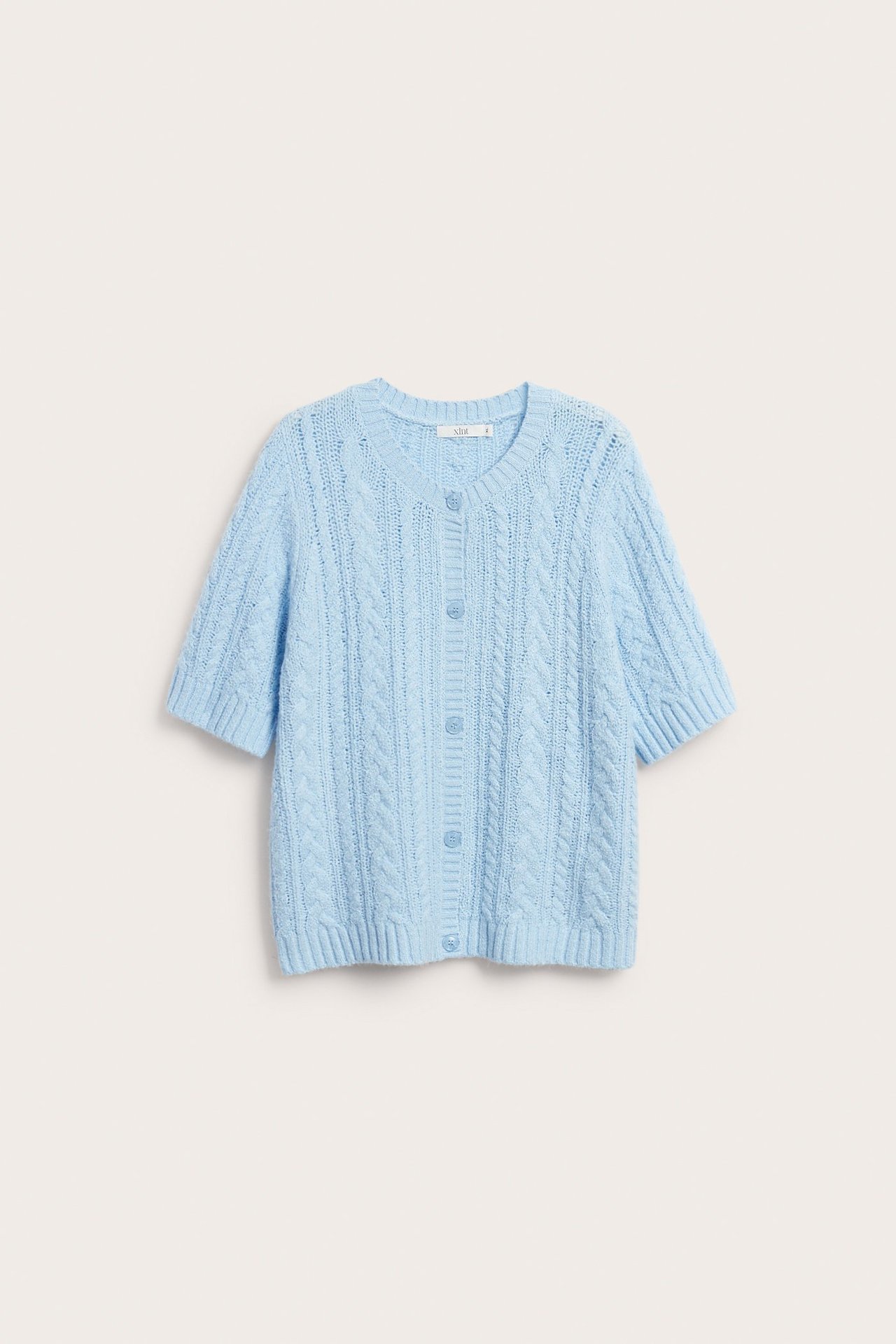 Frontvy av en ljusblå kabelstickad kortärmad kofta med rund hals och knappar fram.