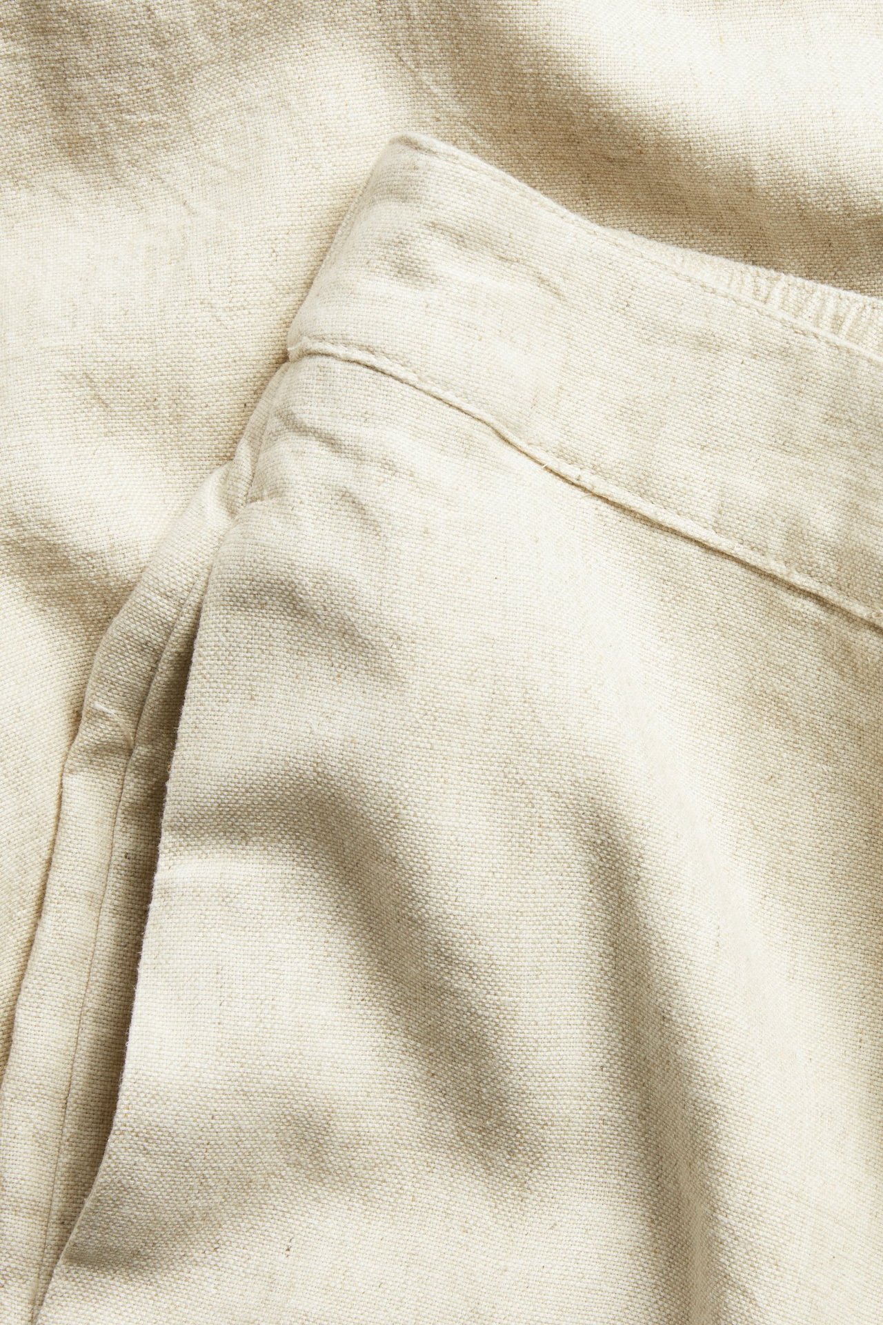 Lähikuva beigemelange pellavasekoite-housuista, joissa rento istuvuus ja sivutasku.