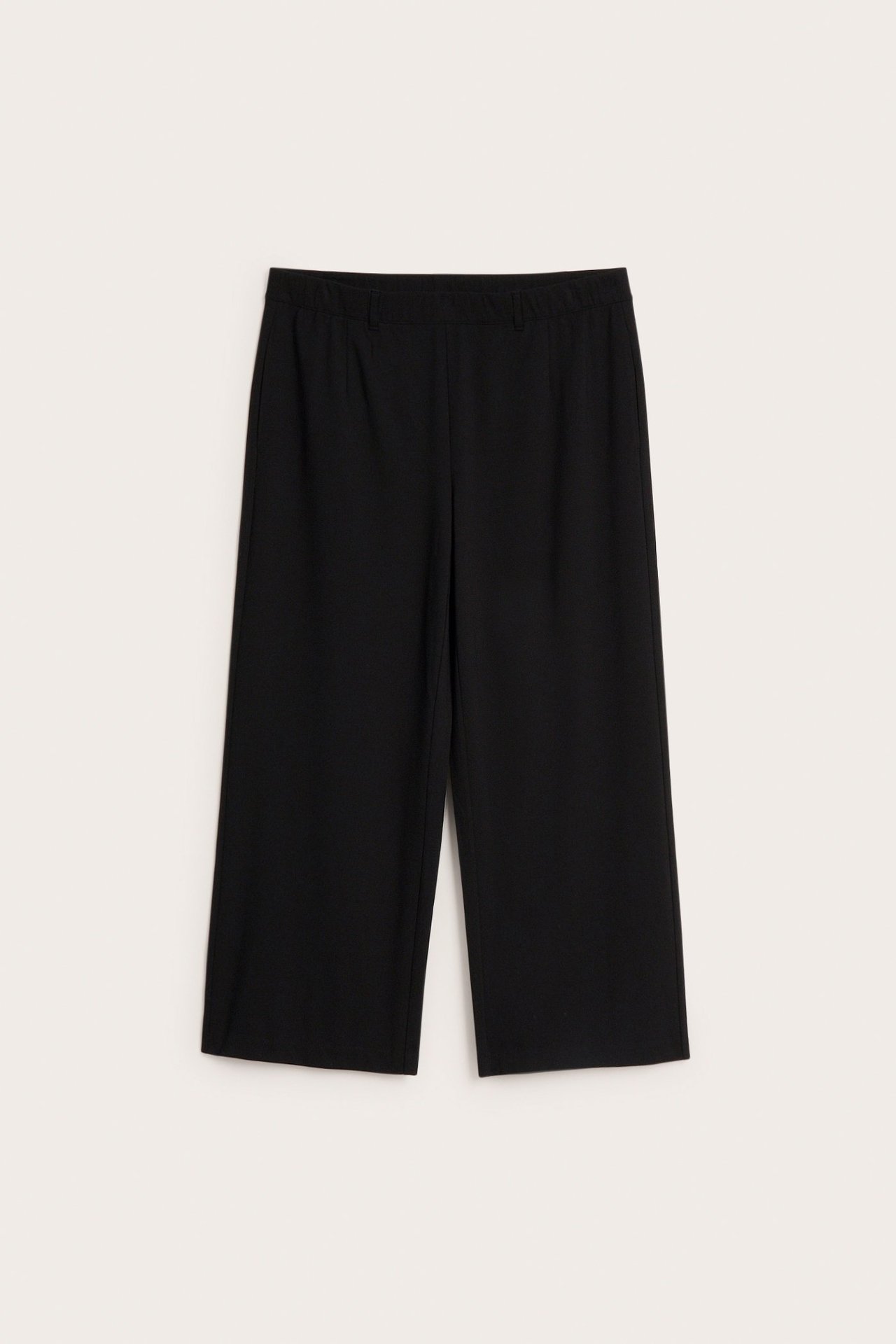 Frontvy av svarta vida, croppade dressade byxor med resår i midjan i slät punto-kvalitet.