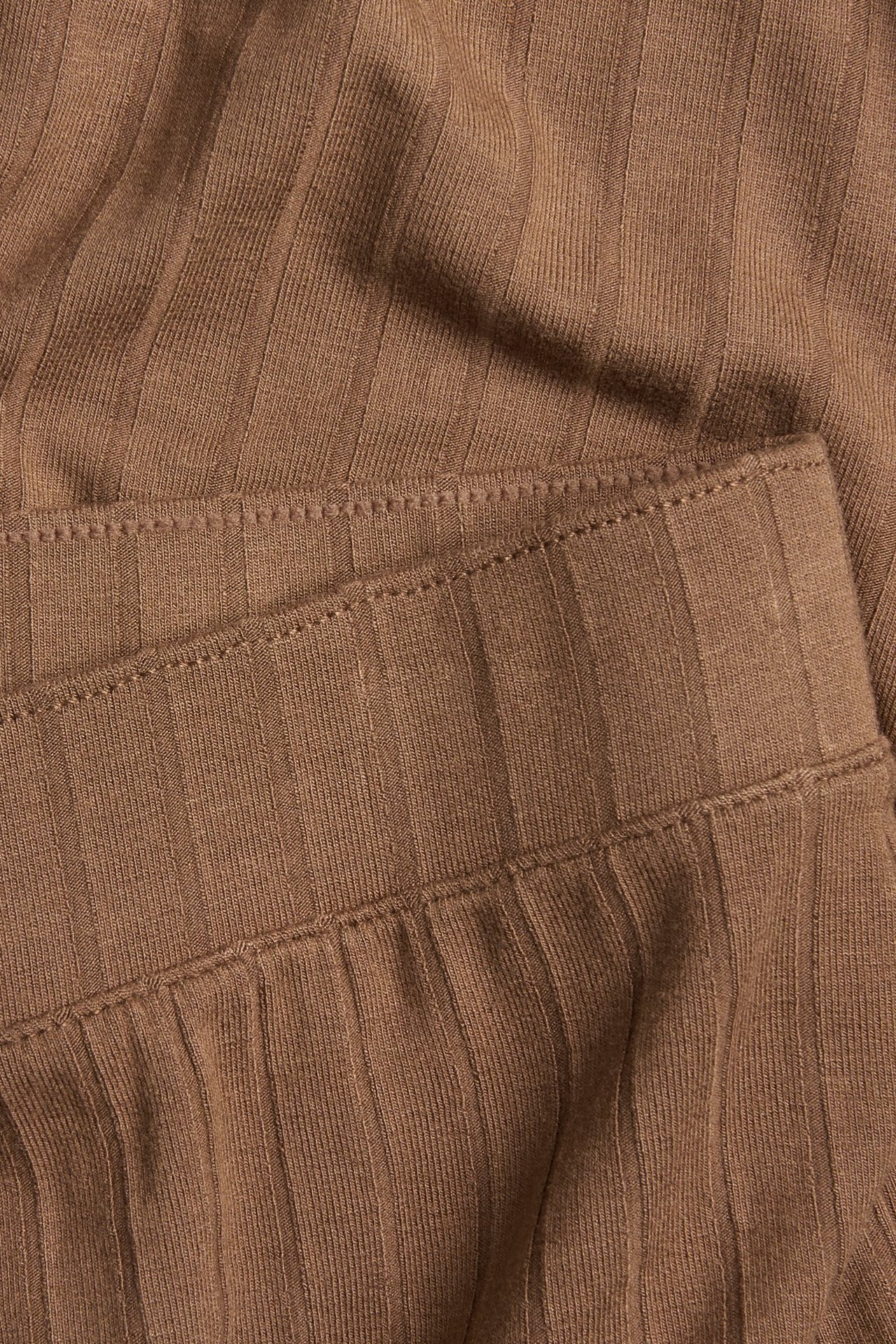 Zbliżenie brązowych, prążkowanych szerokich spodni z wiskozowej dzianiny, z elastyczną talią.