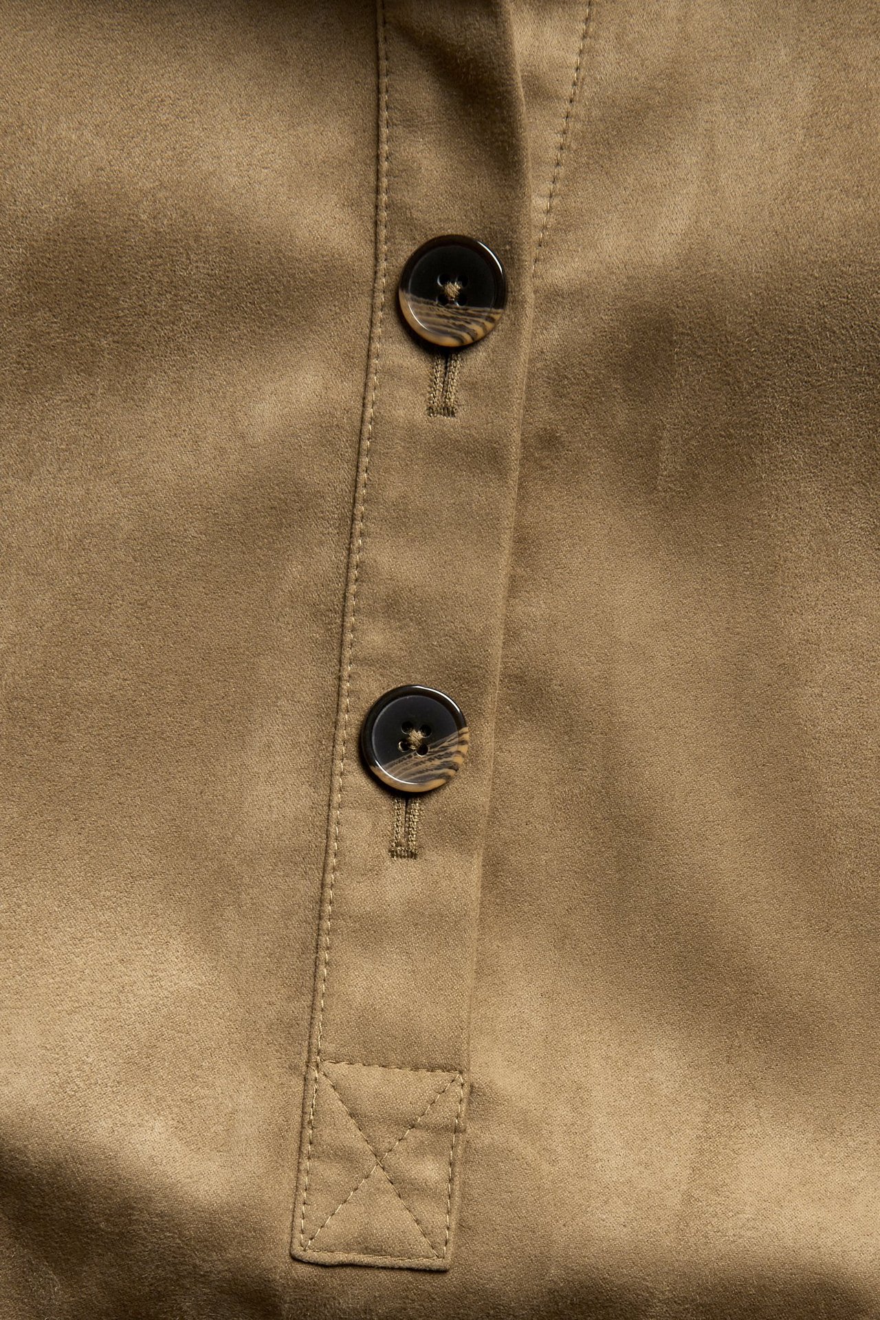 Lähikuva ruskeasta mokkajäljitelmämekosta, jossa on kaksi marmoroitua nappia edessä.