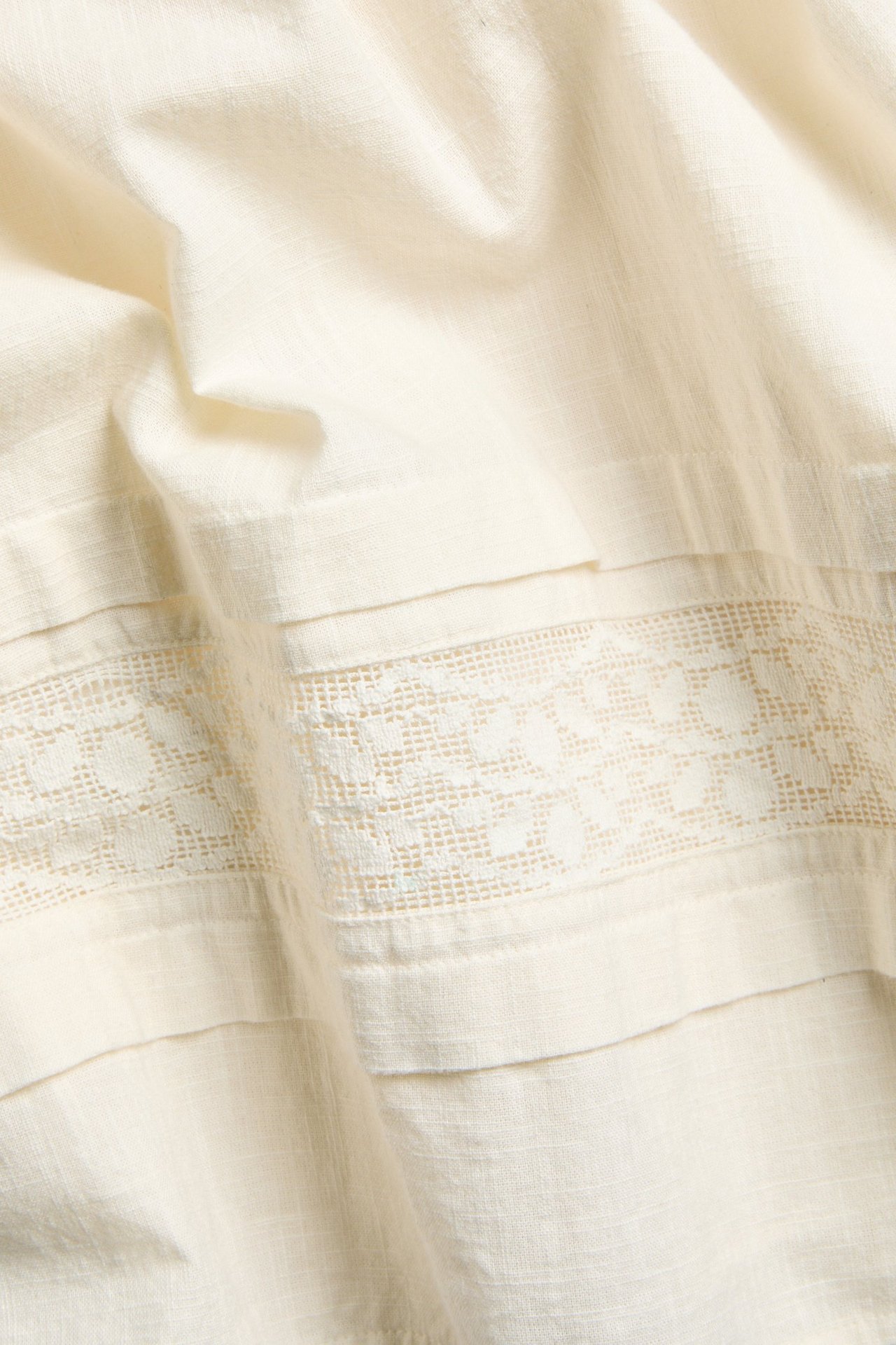 Spódnica bawełniana ecru z poziomym koronkowym paskiem, zbliżenie.