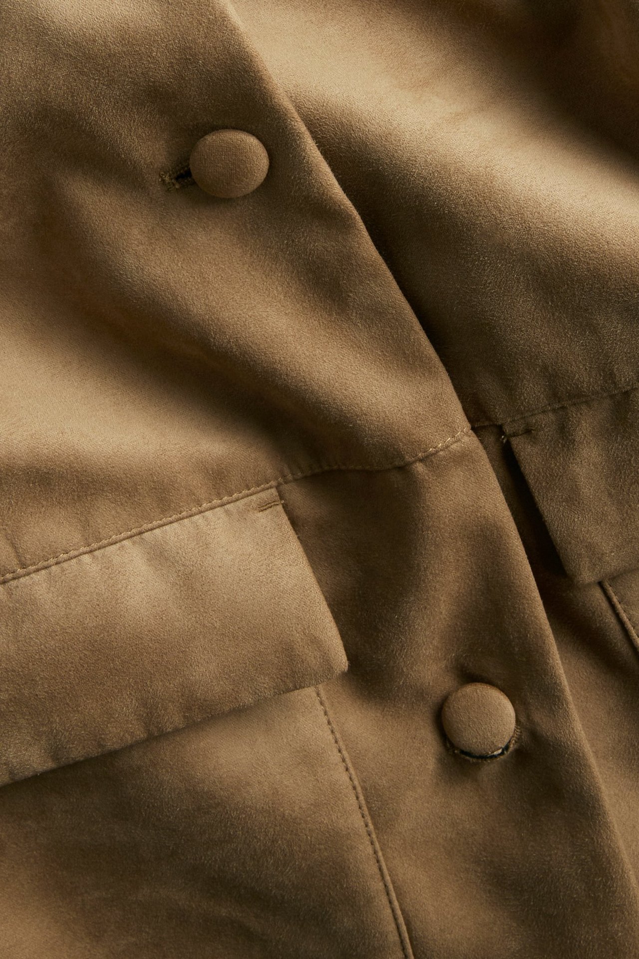 Lähikuva ruskeasta mokkajäljitelmä-takista, jossa napit ja yksityiskohtaiset etutaskut.