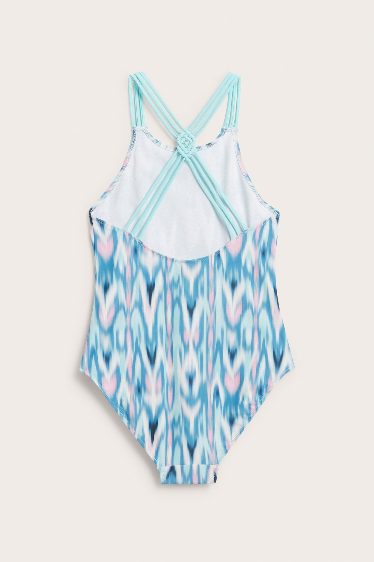 Bakfra, mønstret barnebadedrakt i lys turkis, rosa og blå med kryssende stropper.