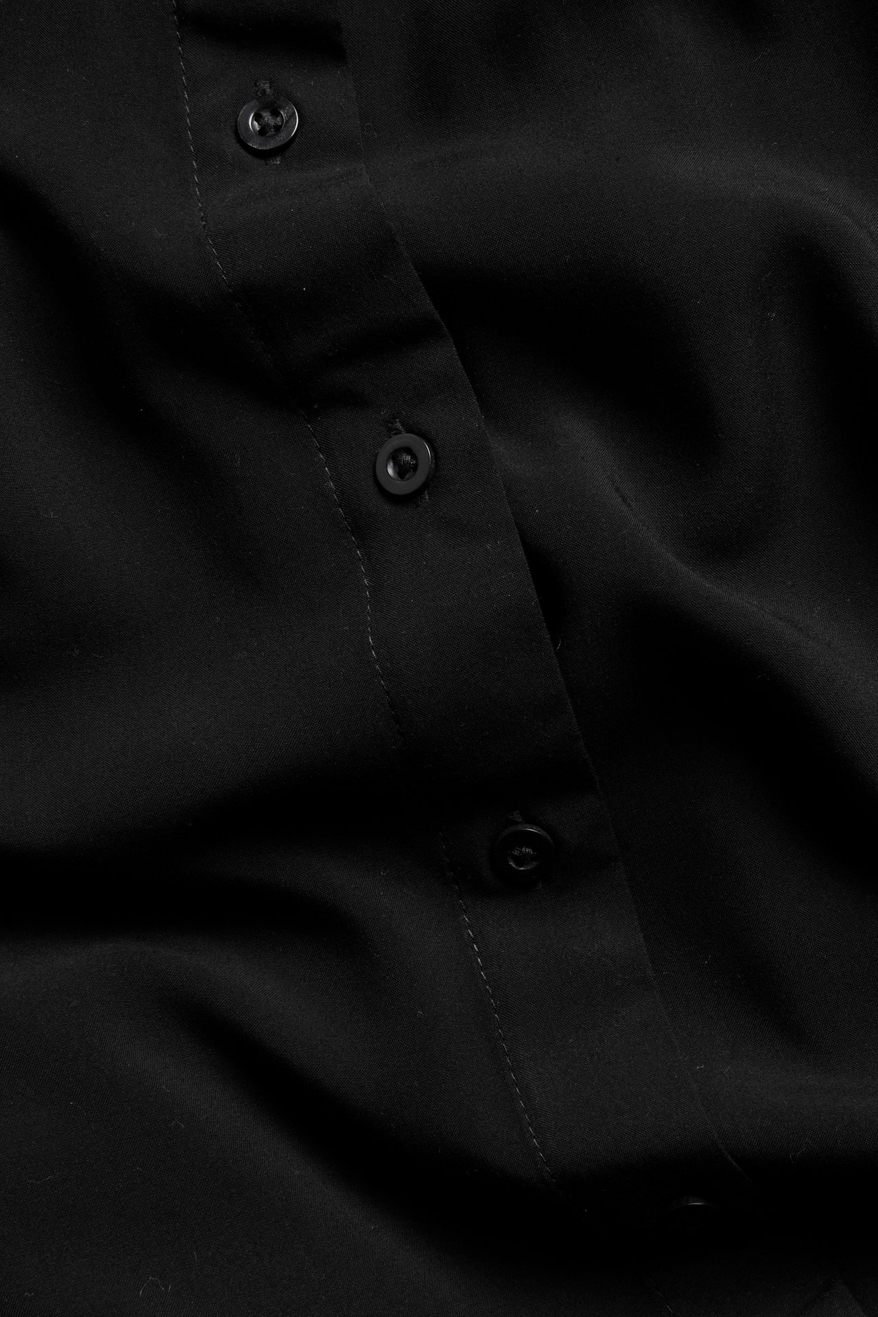 Lähikuva mustasta viskoosipaitamekosta, jossa näkyy nappilista ja yhteensopivat mustat napit.