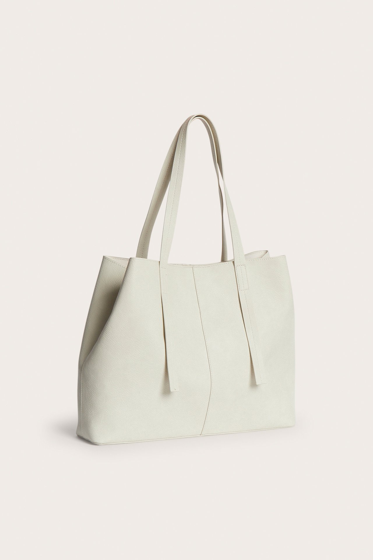 Etuviisto näkymä vaaleasta beigestä keinonahkaisesta ostoskassista kahdella kantokahvalla.