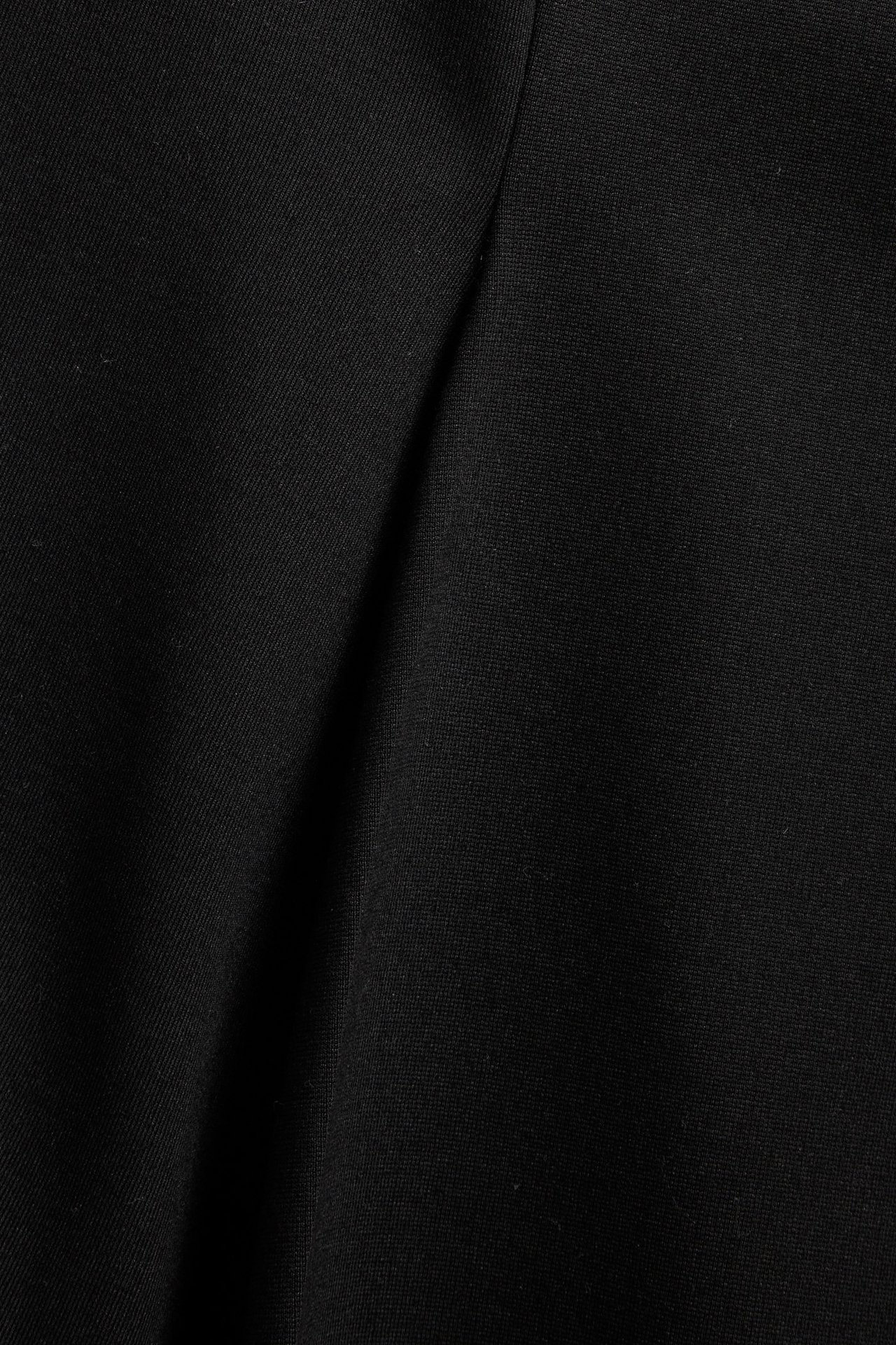 Zbliżenie na czarną tkaninę punto z subtelnymi zagięciami, podkreślające gładką teksturę materiału.