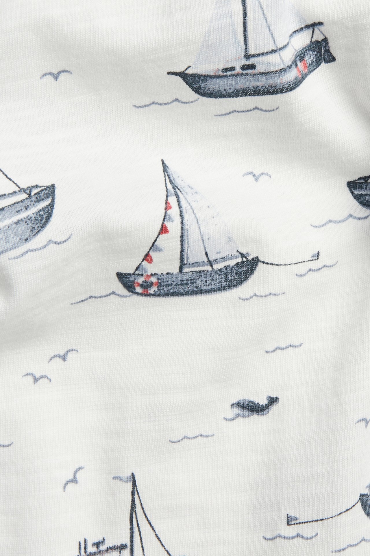 Närbild: offwhite T-shirt i slubtrikå med heltäckande segelbåtsmönster.