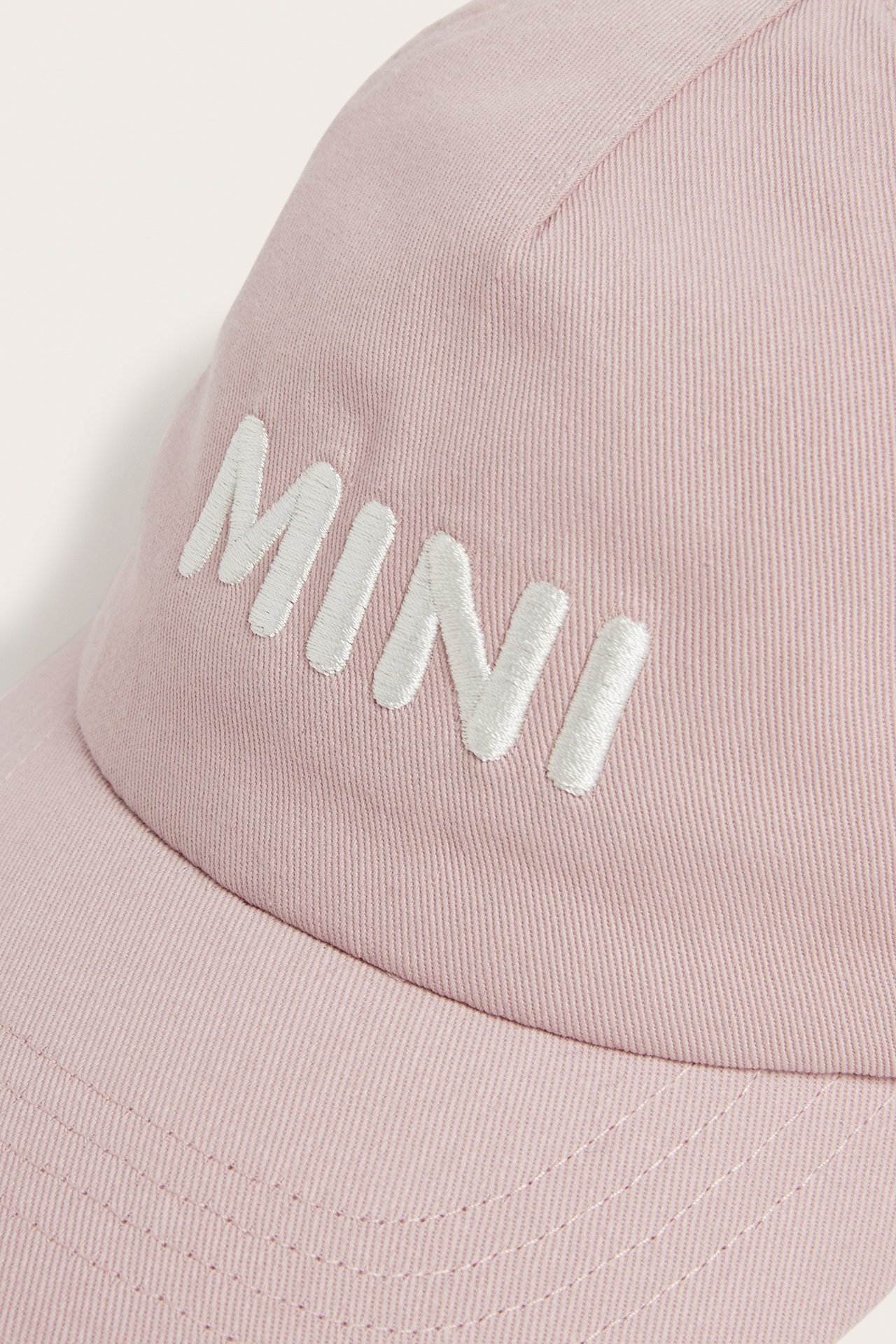 Lähikuva edestä vaaleanpunaisesta puuvillalipallakista, jossa valkoinen 'MINI'-kirjonta.