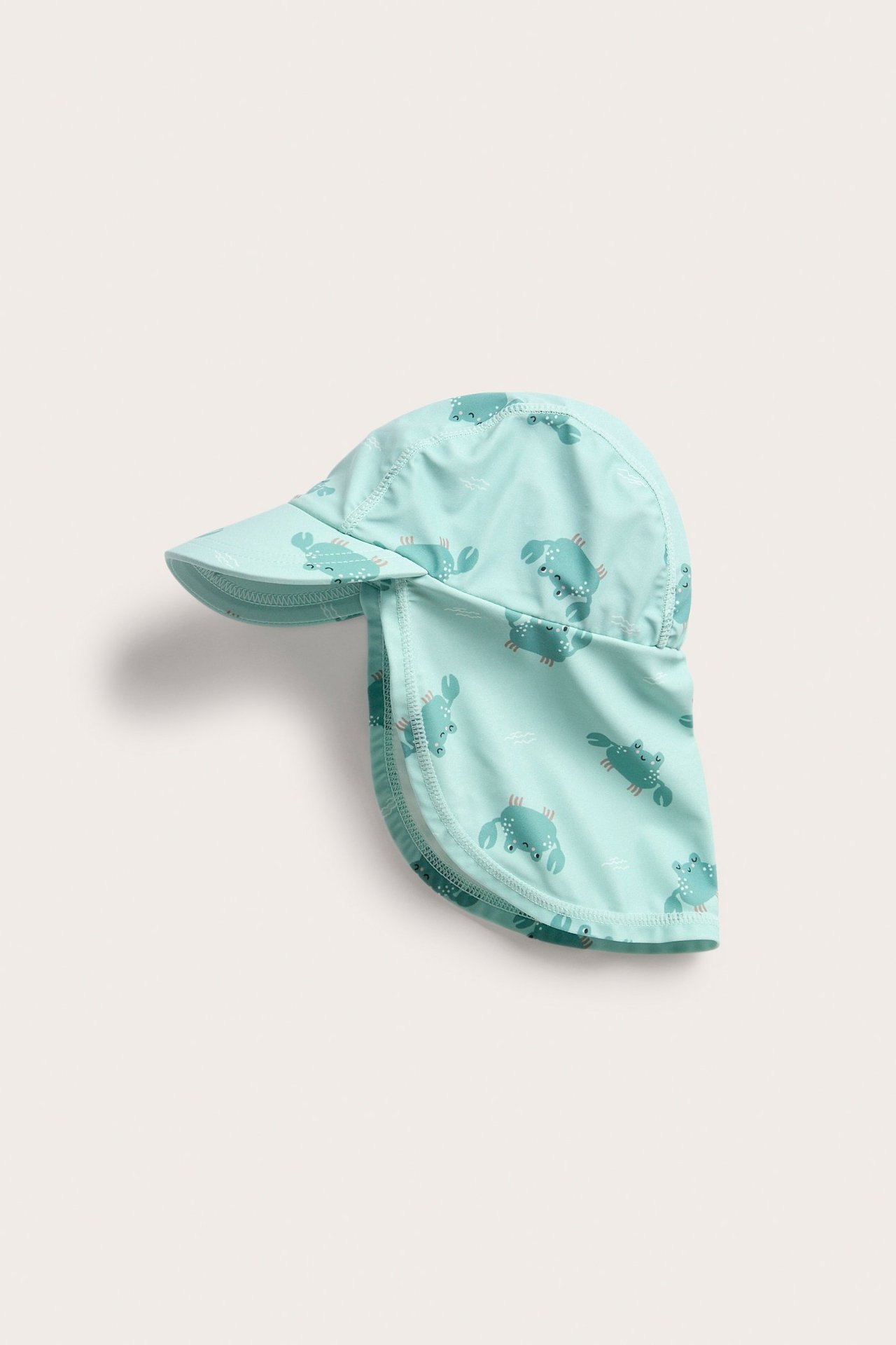 Frontbilde av en lyse turkis UV-caps med nakkebeskyttelse, mønstret med små krabber.