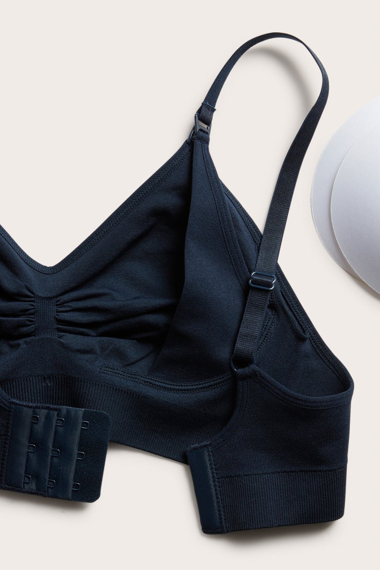 Närbild av en mörkblå sömlös amningsbh med justerbara band, hyskknäppning och två vita uttagbara inlägg.